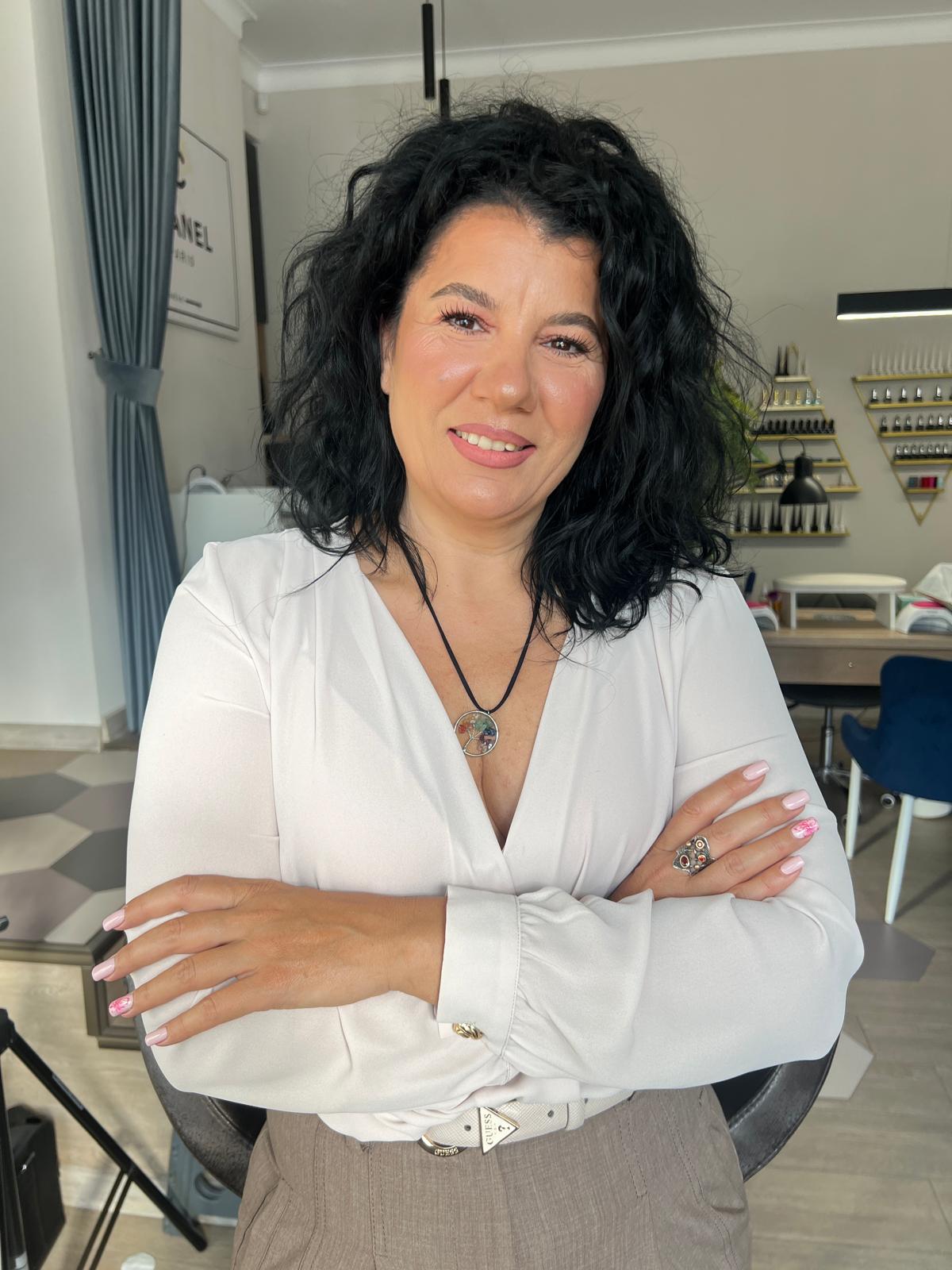 A person with curly hair sits at a desk, working on a laptop in a cozy, well-lit environment.