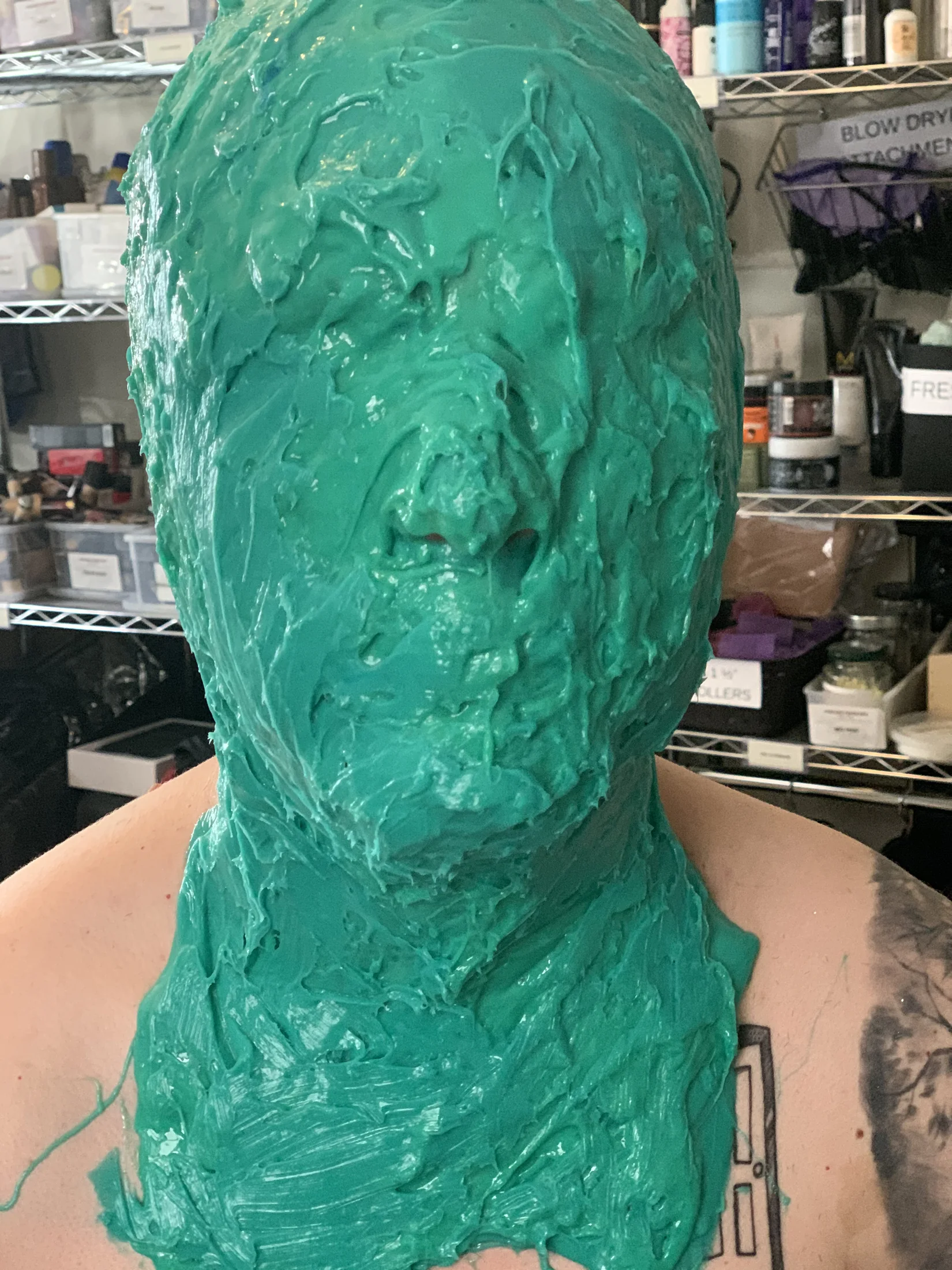 Performer covered in green molding material during the creature transformation process