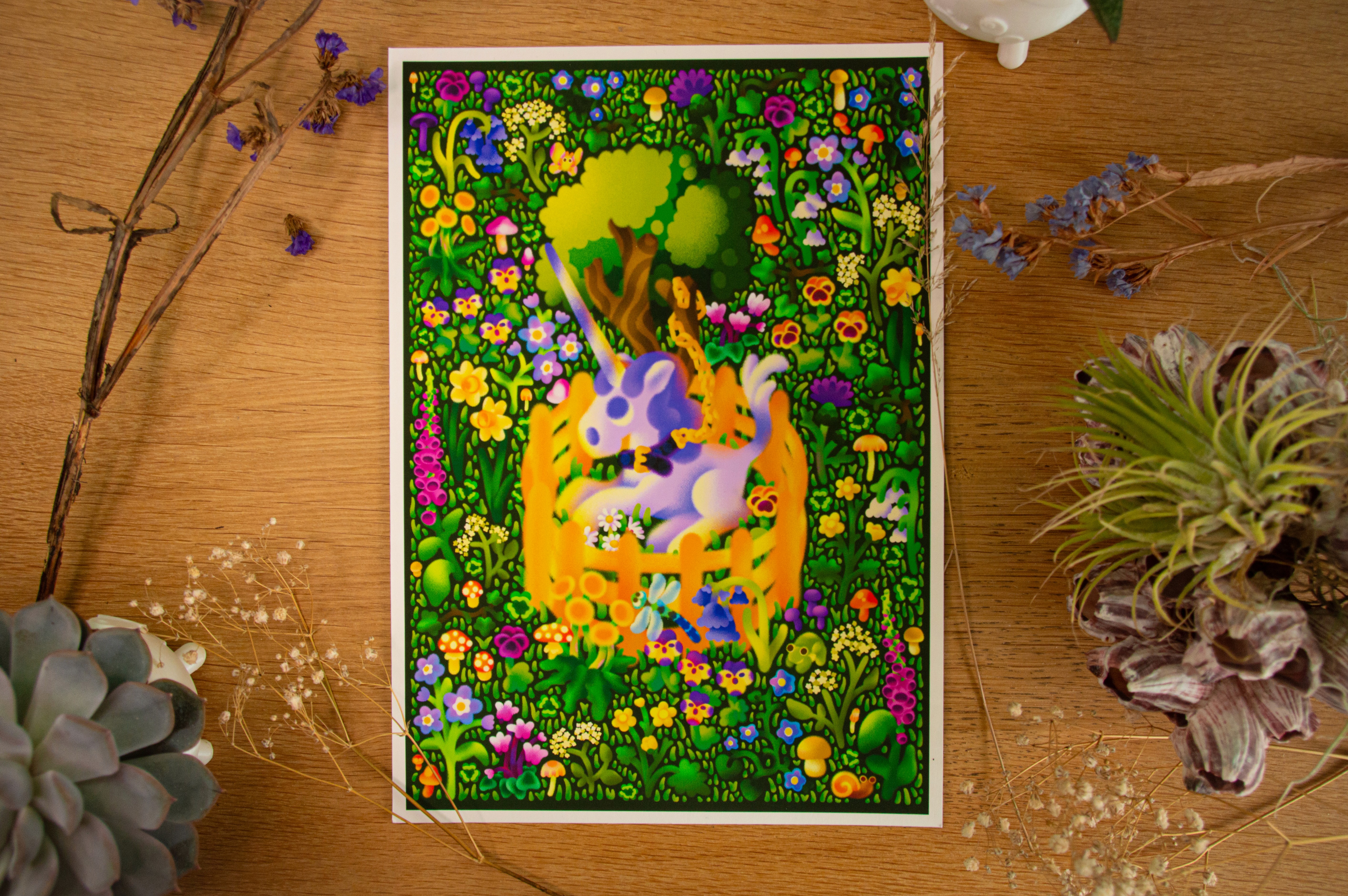 The artwork as a fine art print, displayed on a wooden table, surrounded by plants.