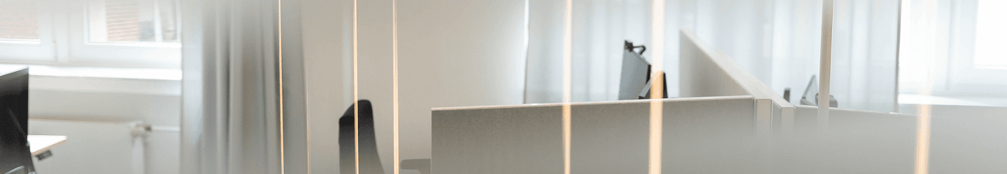 Minimalistische Empfangssituation bei SLB mit hellem Tresen, Glaswand und viel Licht im Hintergrund.