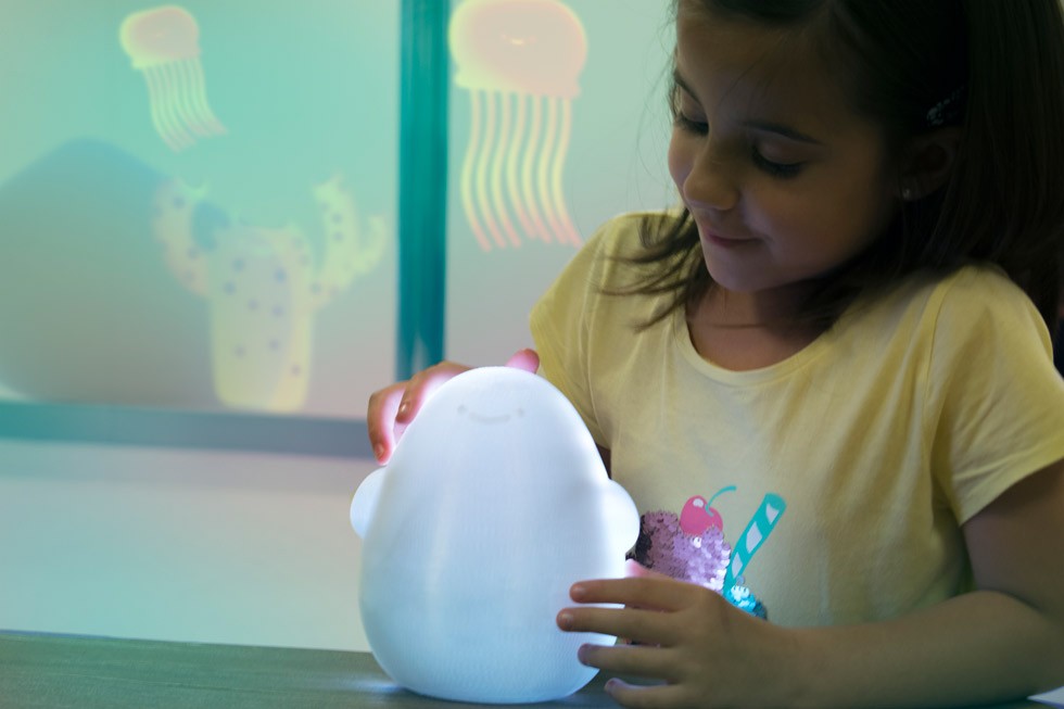Young child holding the Globulus device, a soft rounded companion object with glowing light elements