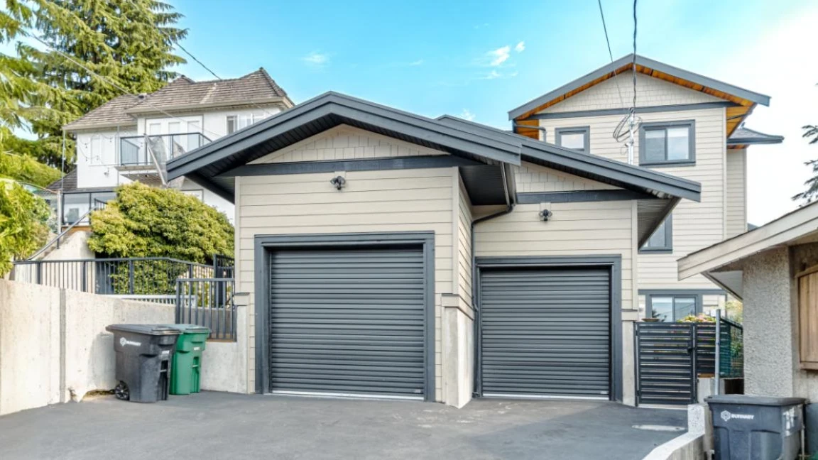 Exterior view of custom-built home in Burnaby featuring dual garage doors and beige siding by Vancouver Custom Homes