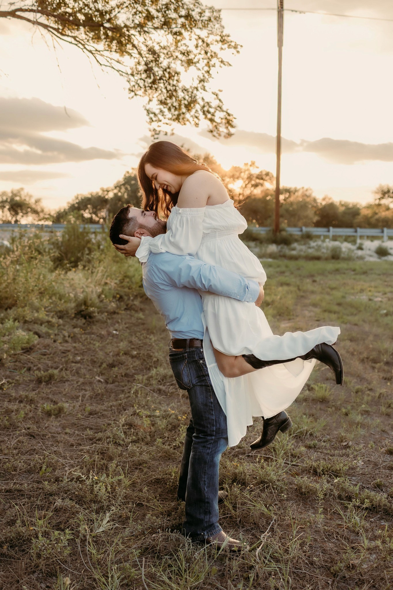 A couple stands outdoors at sunset.