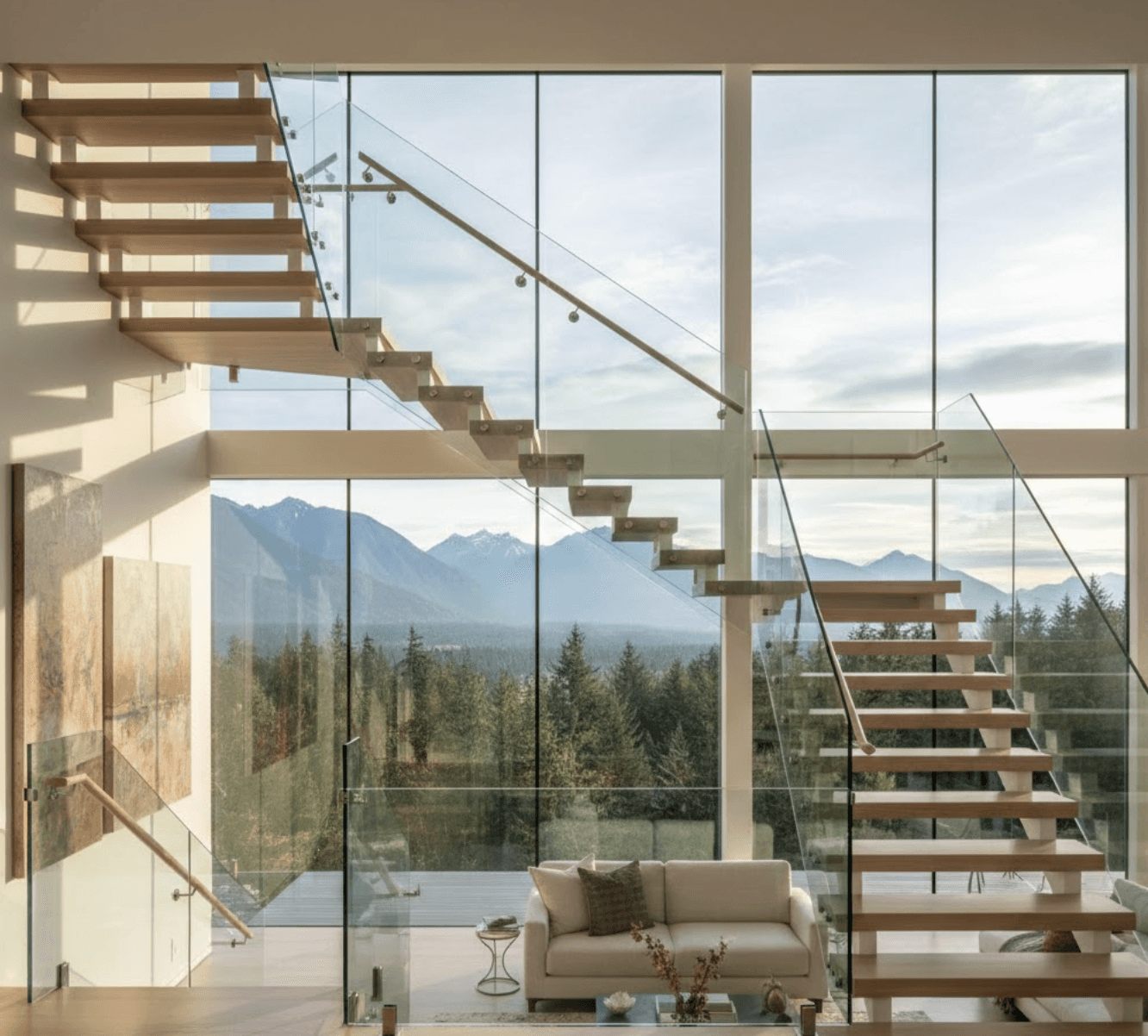 Modern floating glass staircase in bright Pacific Northwest home interior. Floor-to-ceiling windows showing mountain and forest view. White oak treads, frameless glass balustrade, minimal stainless hardware. Natural light flooding space. West Coast contemporary aesthetic. Photorealistic architectural photography, 16:9 aspect ratio, warm afternoon lighting.