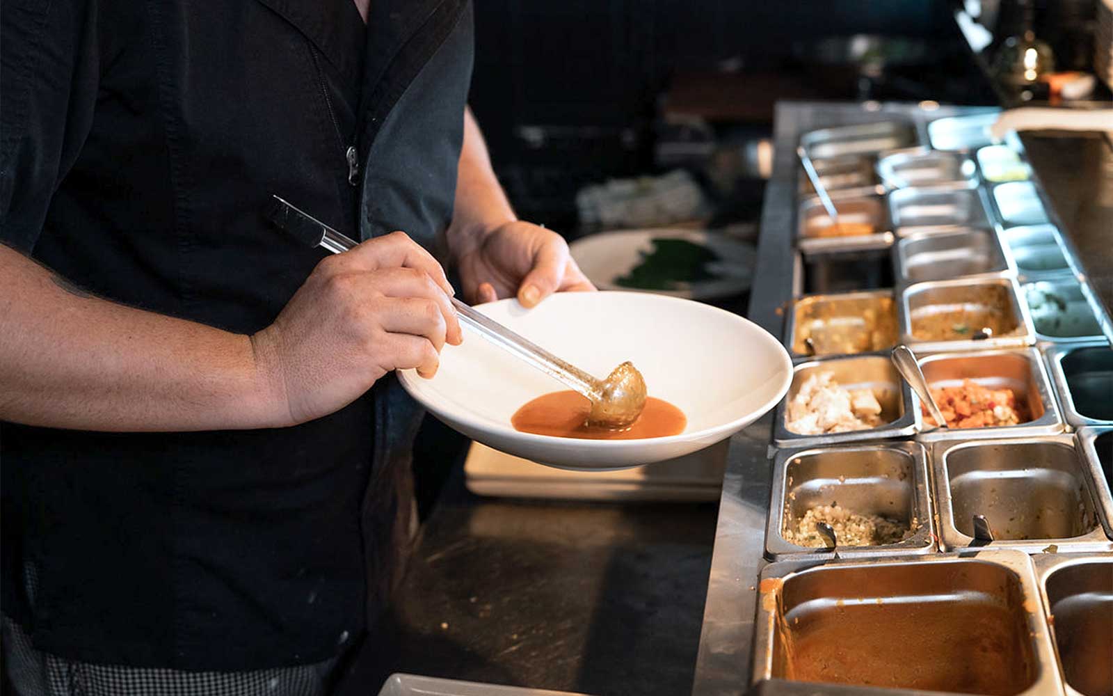 Chef preparing gourmet dish with sauce during 3.5-hour lunch or dinner art tour.