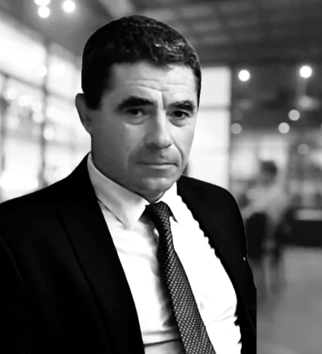 Black and white photo of a cauzazian man dressed in suit and tie with a blured office background