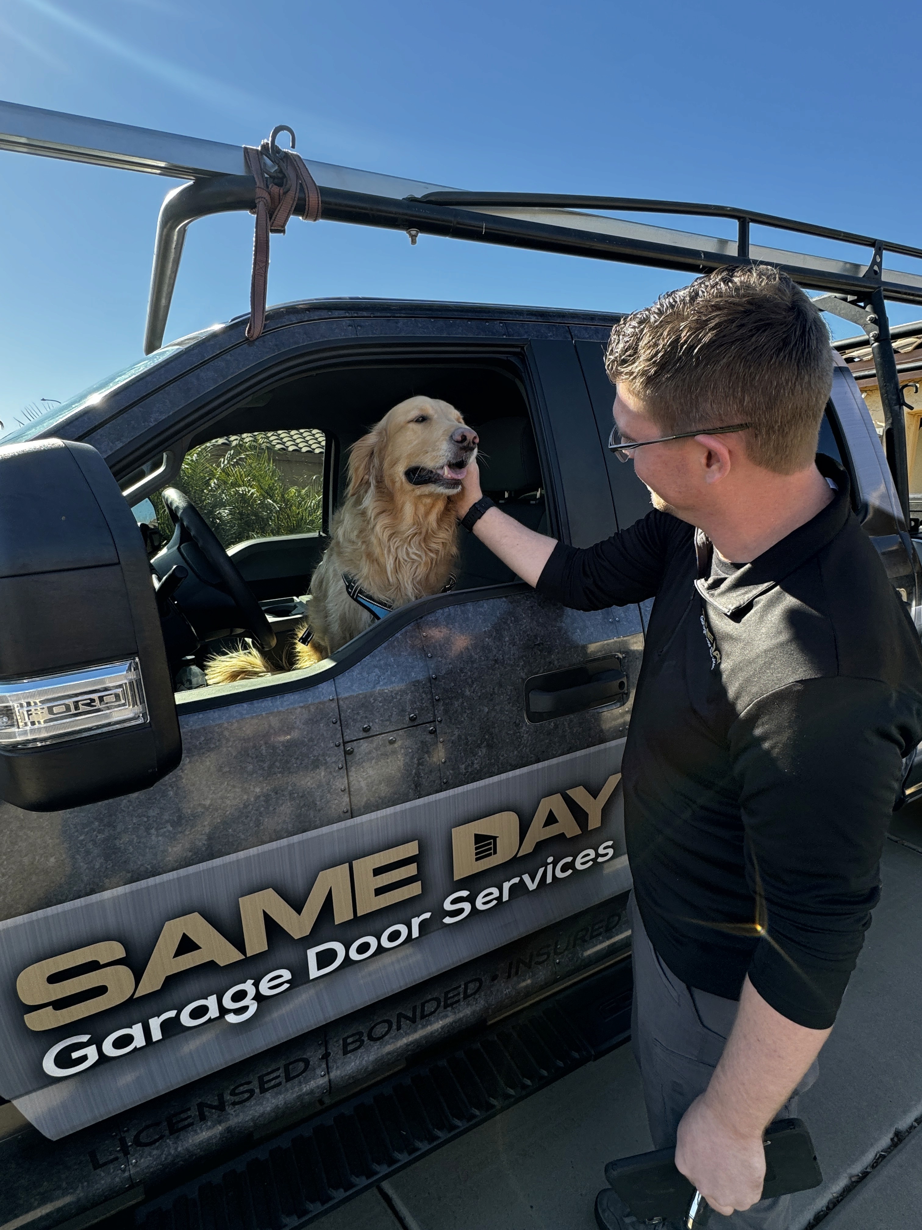 Same Day Garage Door Services Technician petting a goldren retriever through an open window in a same day garage door services branded truck