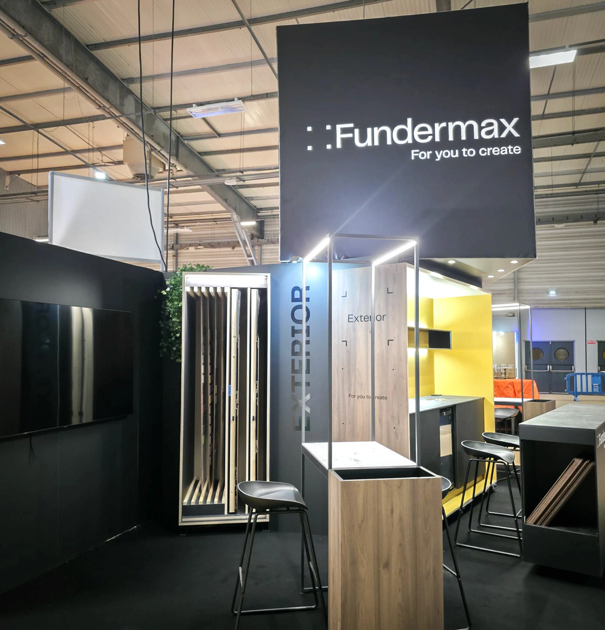 Stand Fundermax panneaux HPL et stratifiés compacts conçu par EXPACE au Carrefour International du Bois (CIB) 2026 — cube noir suspendu, pôles Interior et Exterior et tours d'échantillons de décors