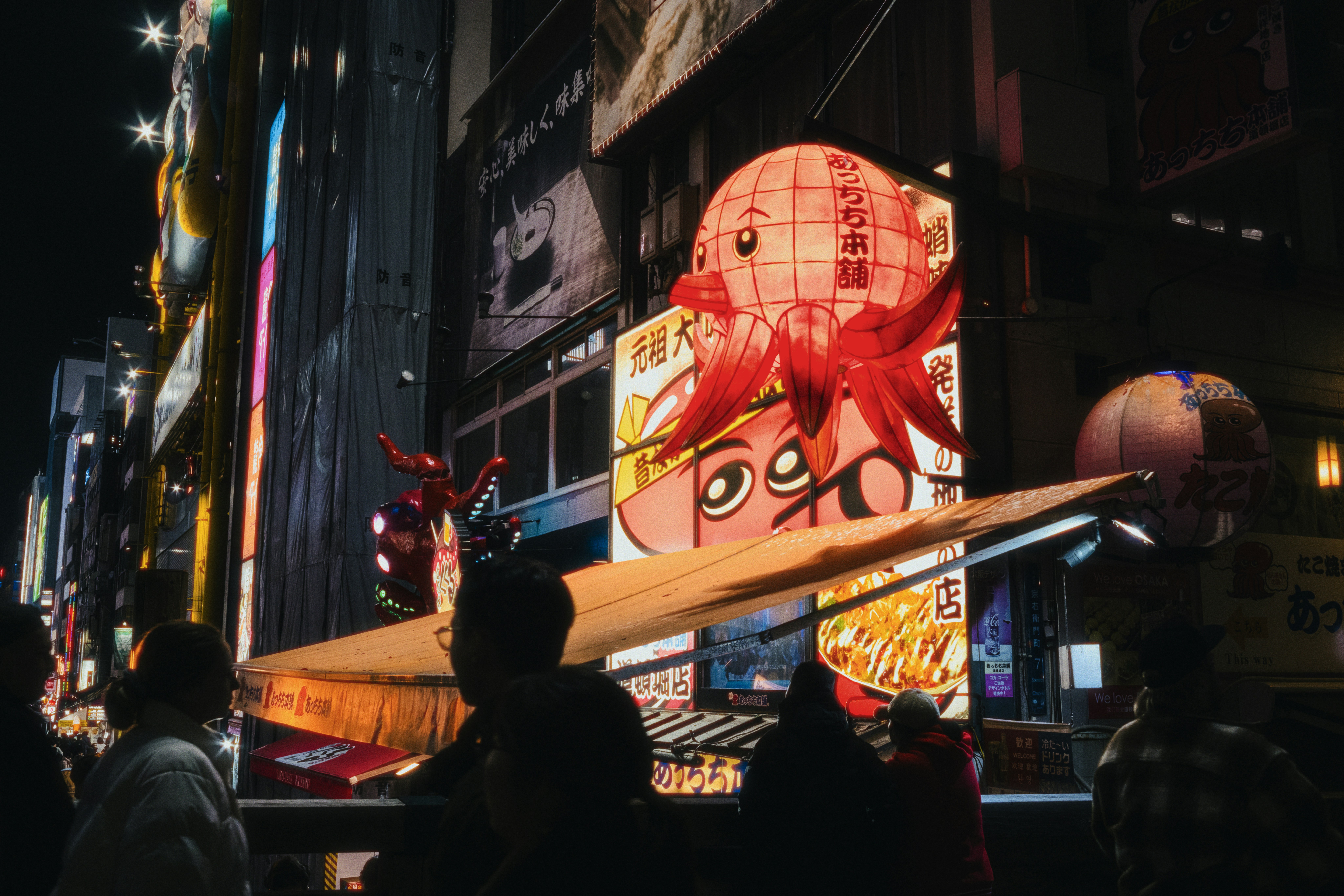 Bright neon signs illuminate a busy city street at night.