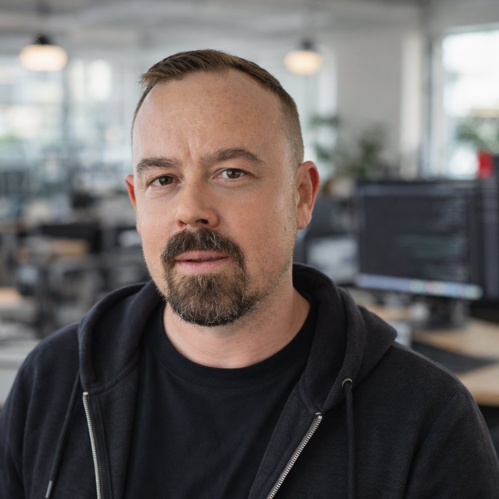 Man with styled hair and beard wearing black shirt.