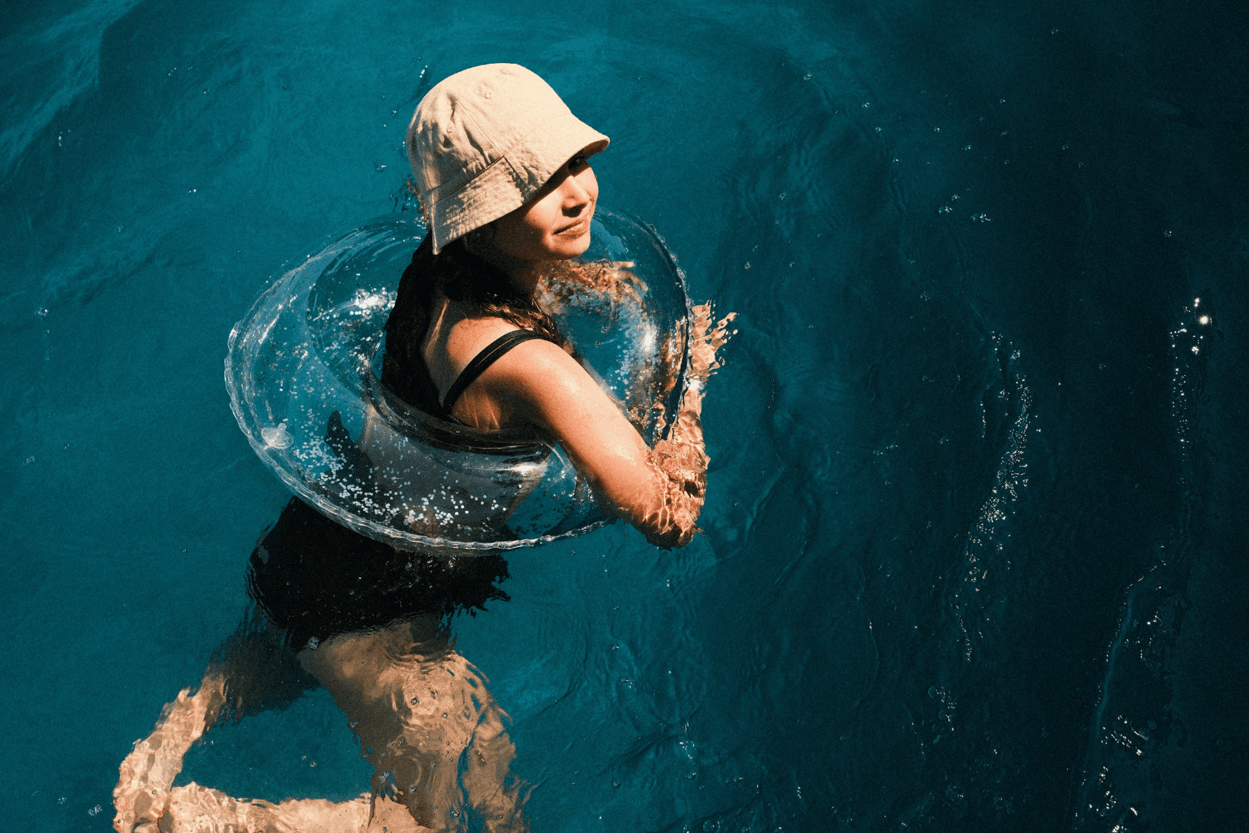 Woman with khaki bucket hat on floating in lake water