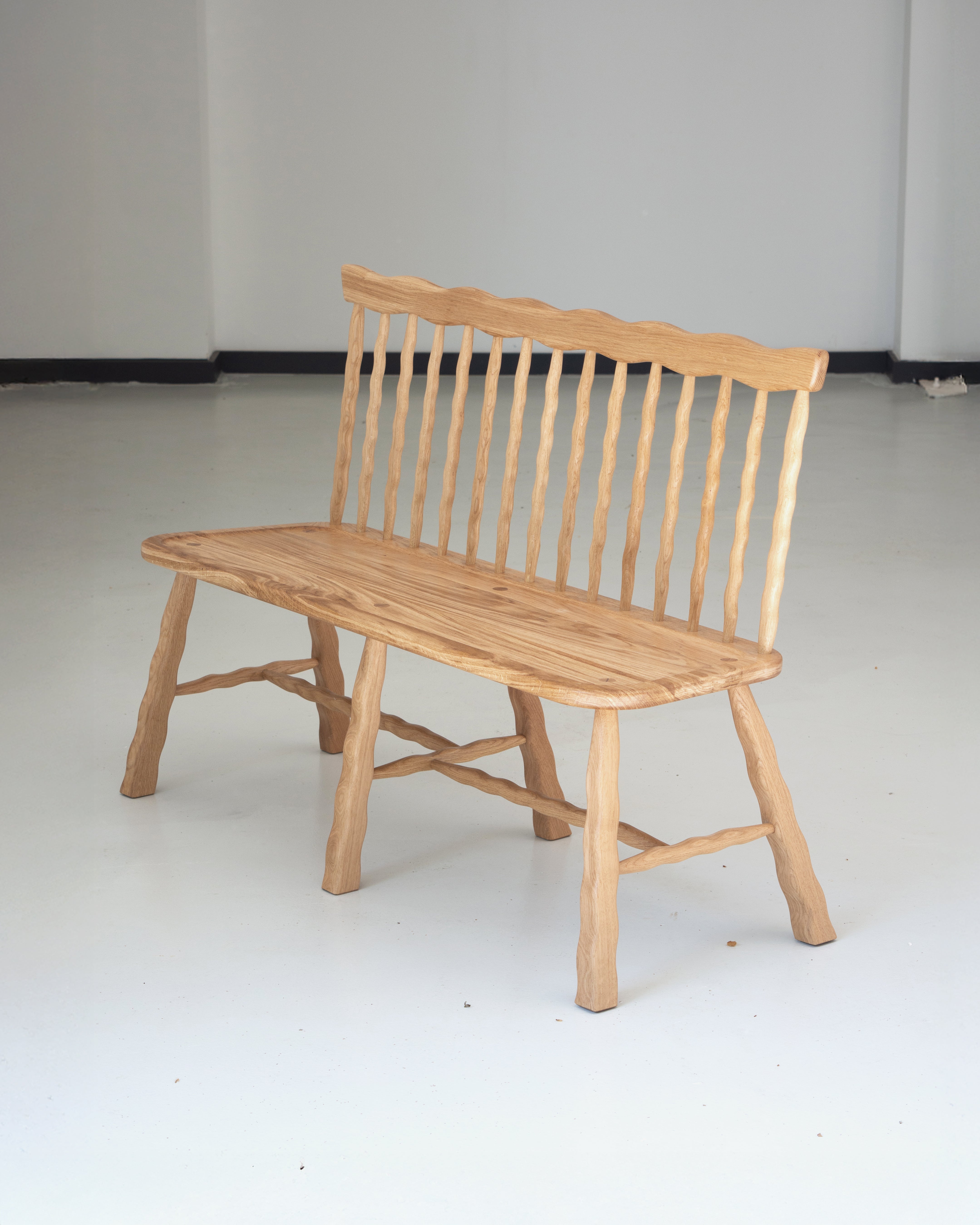 Wooden bench with wavy backrest on a plain white background