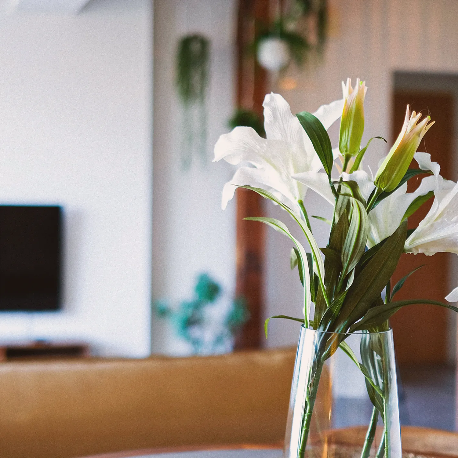 Loft N°3 • white lilies in a glass vase with the living room in the background