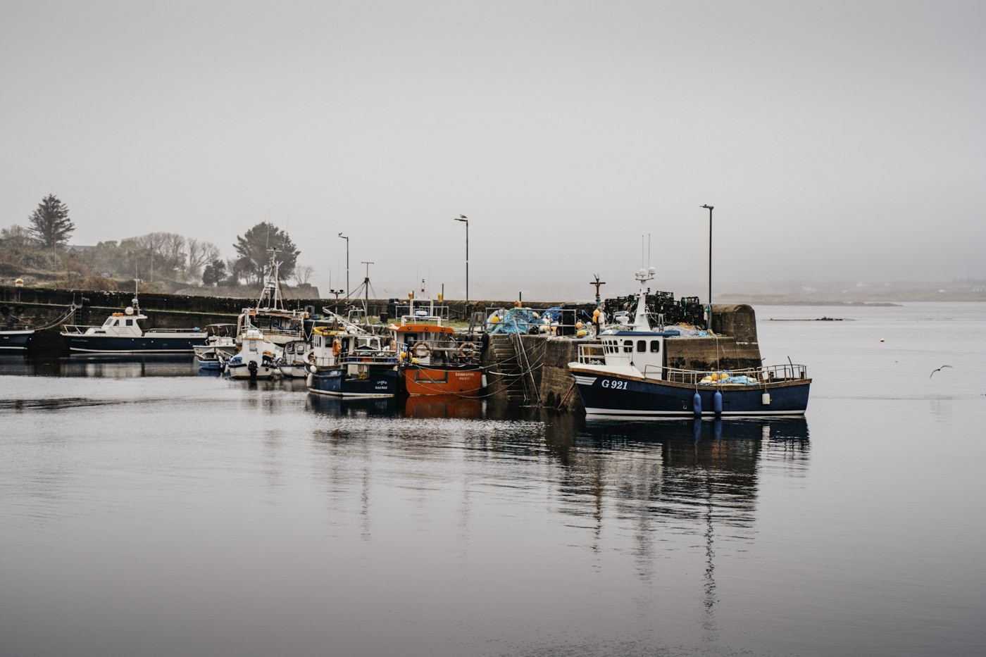 Fishing boats docked at a harbor on a foggy day
