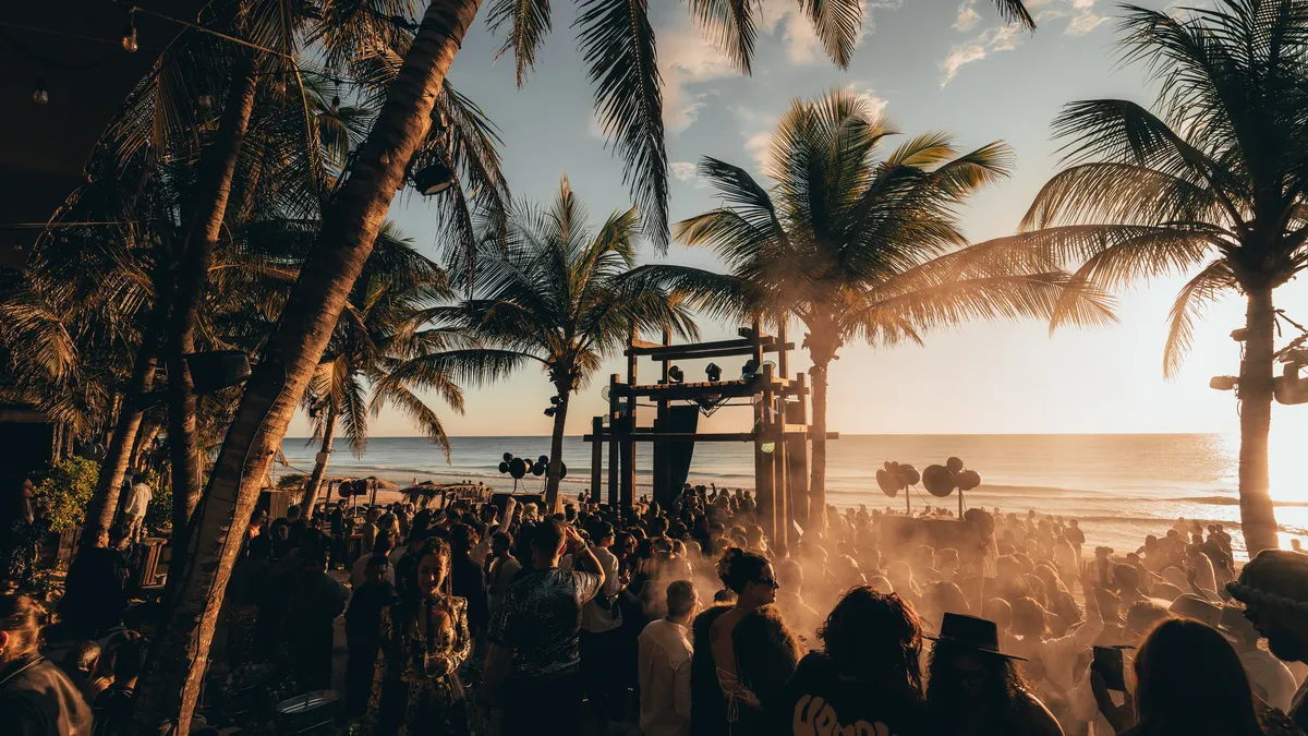 Group of people dancing and having fun on the beach in Nomade Tulum Mexico, with live music playing in the background