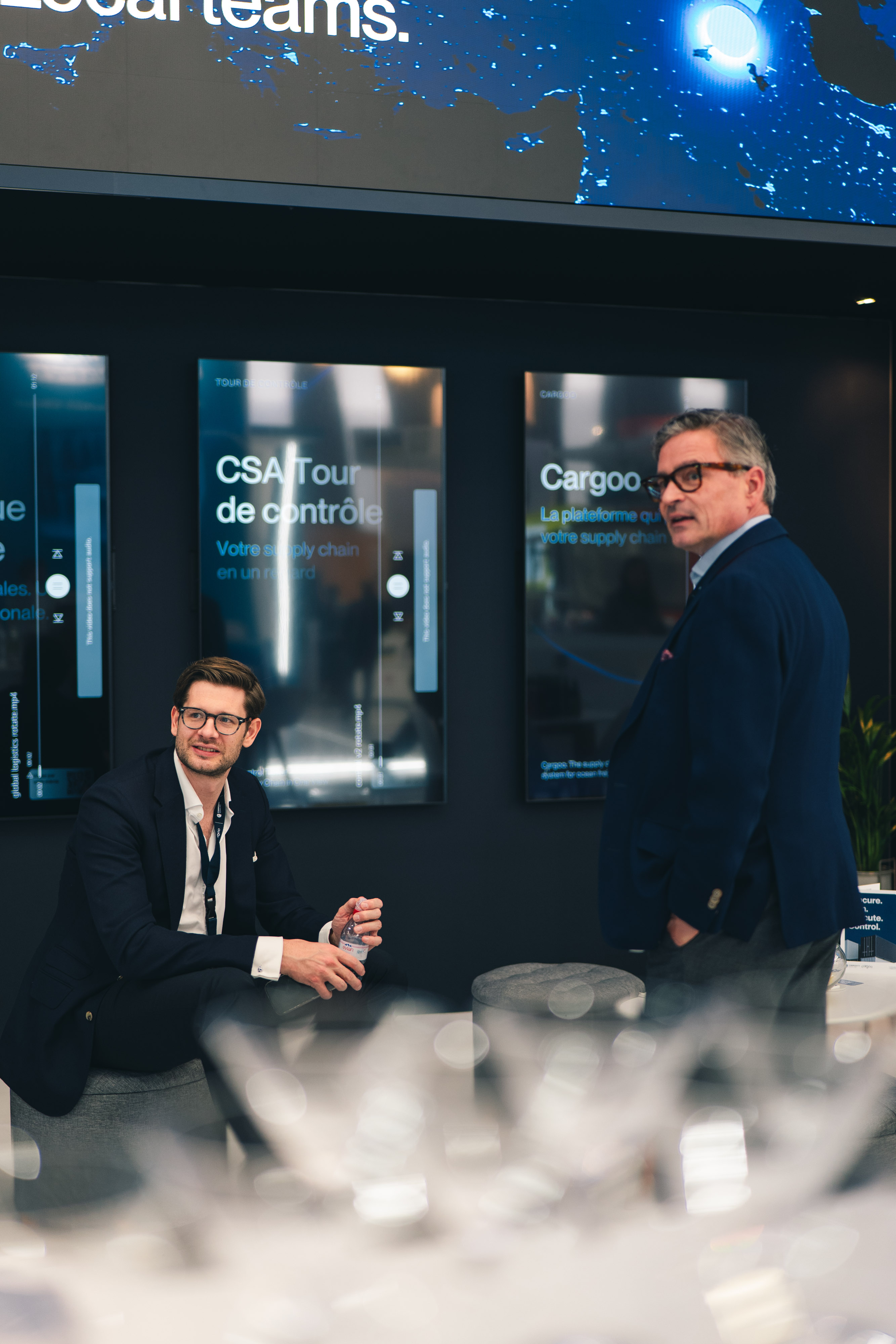 Two logistics experts in conversation at a CSA and Cargoo event booth.
