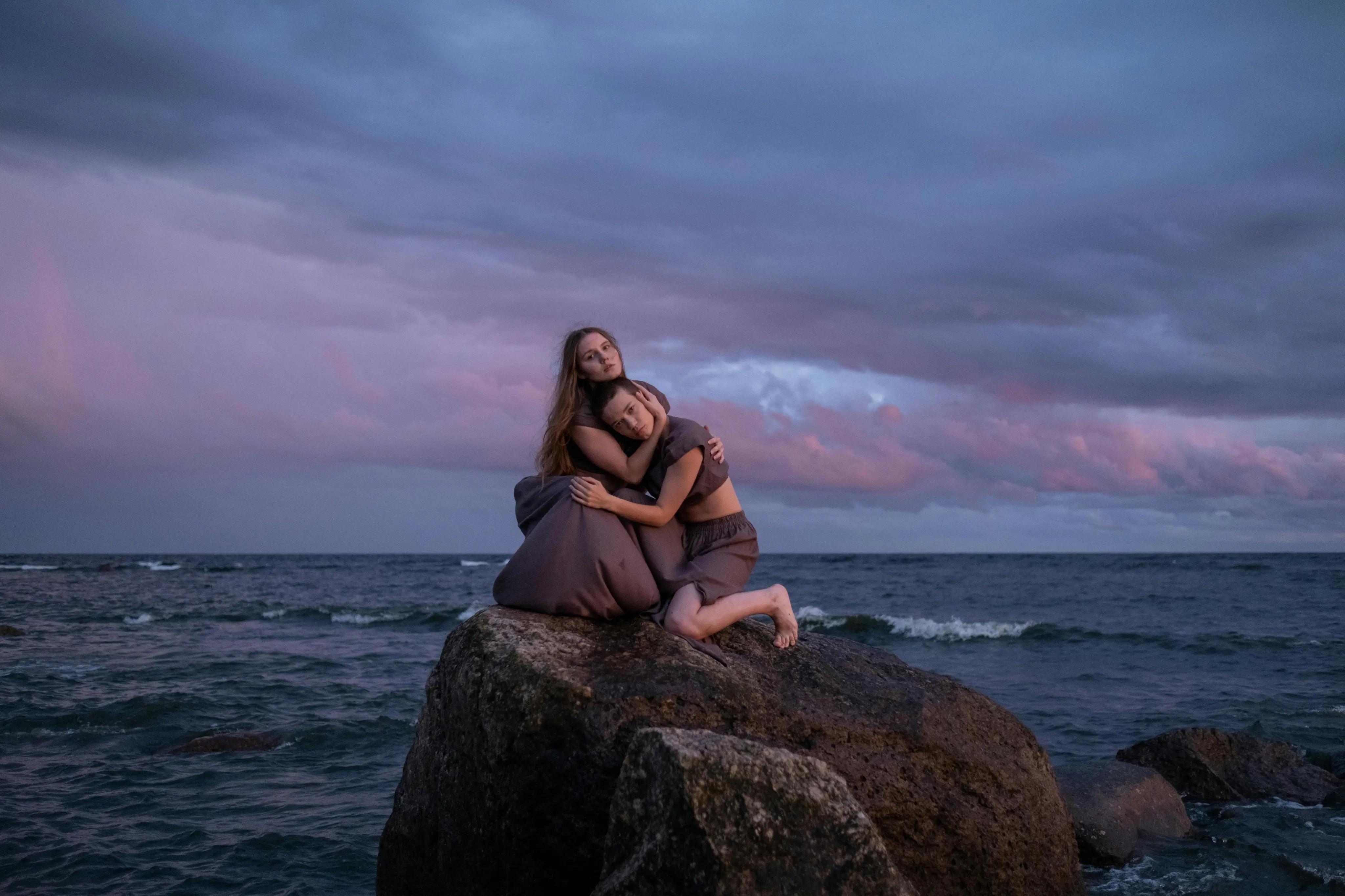 Emma Rivera & Lily Martinez are posing at seaside on stone