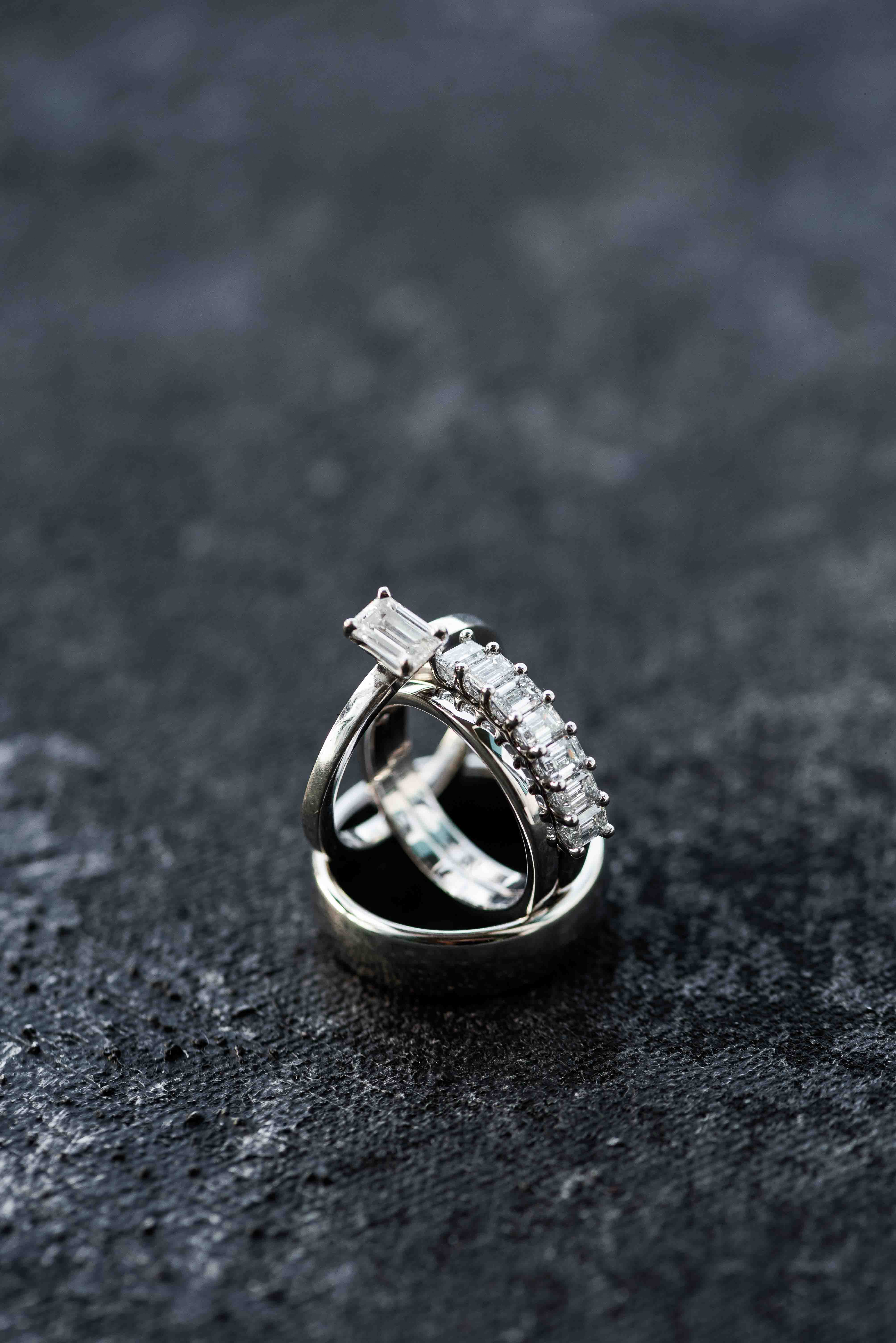 Ring shot of bride and groom's wedding bands on a hand painted black backdrop.