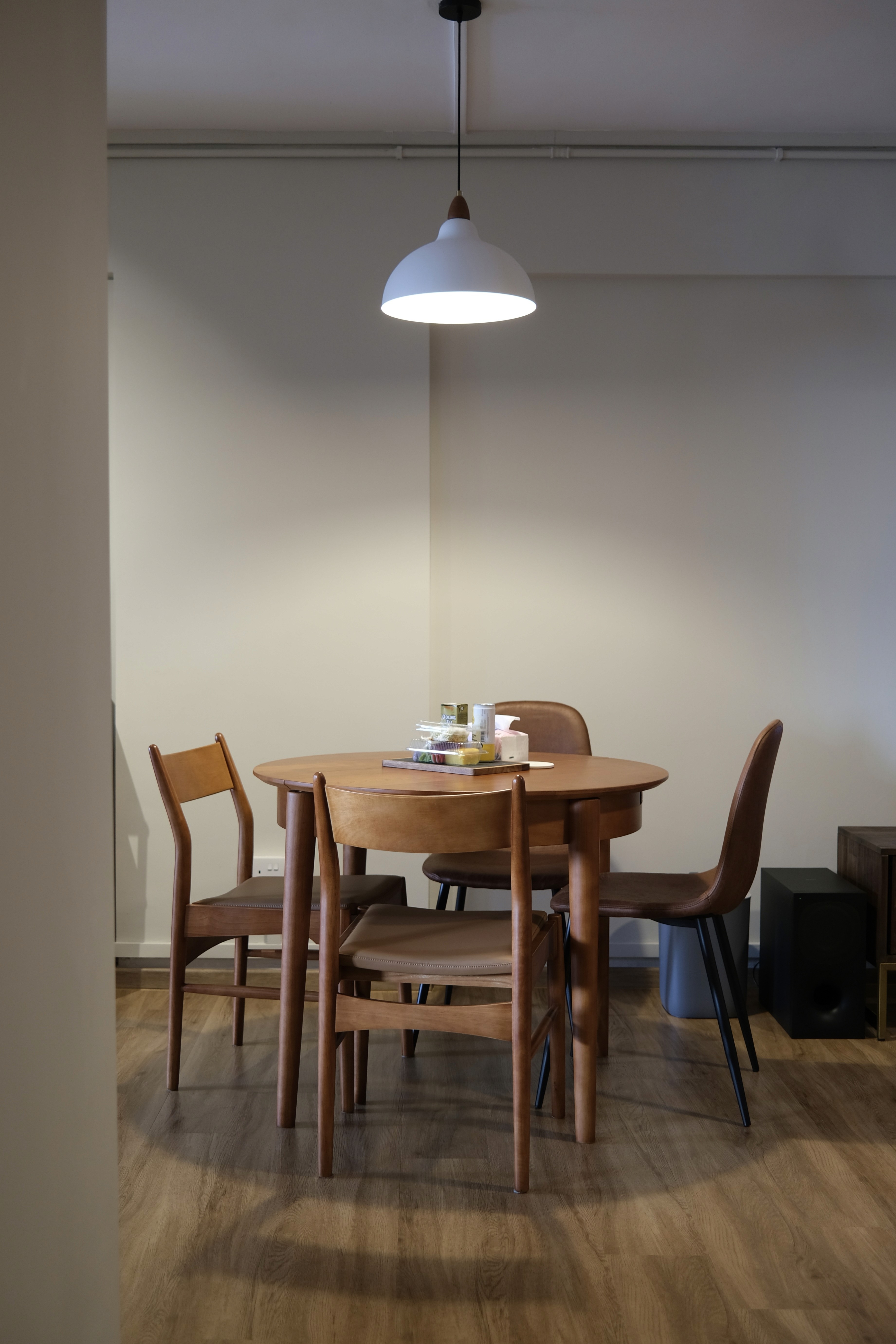 A compact dining setting anchored by natural wood furniture and soft pendant lighting, designed to encourage everyday gatherings in a quiet, uncluttered atmosphere.