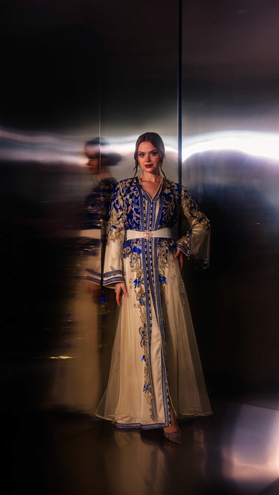 Ivory Moroccan caftan with deep blue embroidery, handcrafted couture piece combining Bahrain atelier and Moroccan artisans