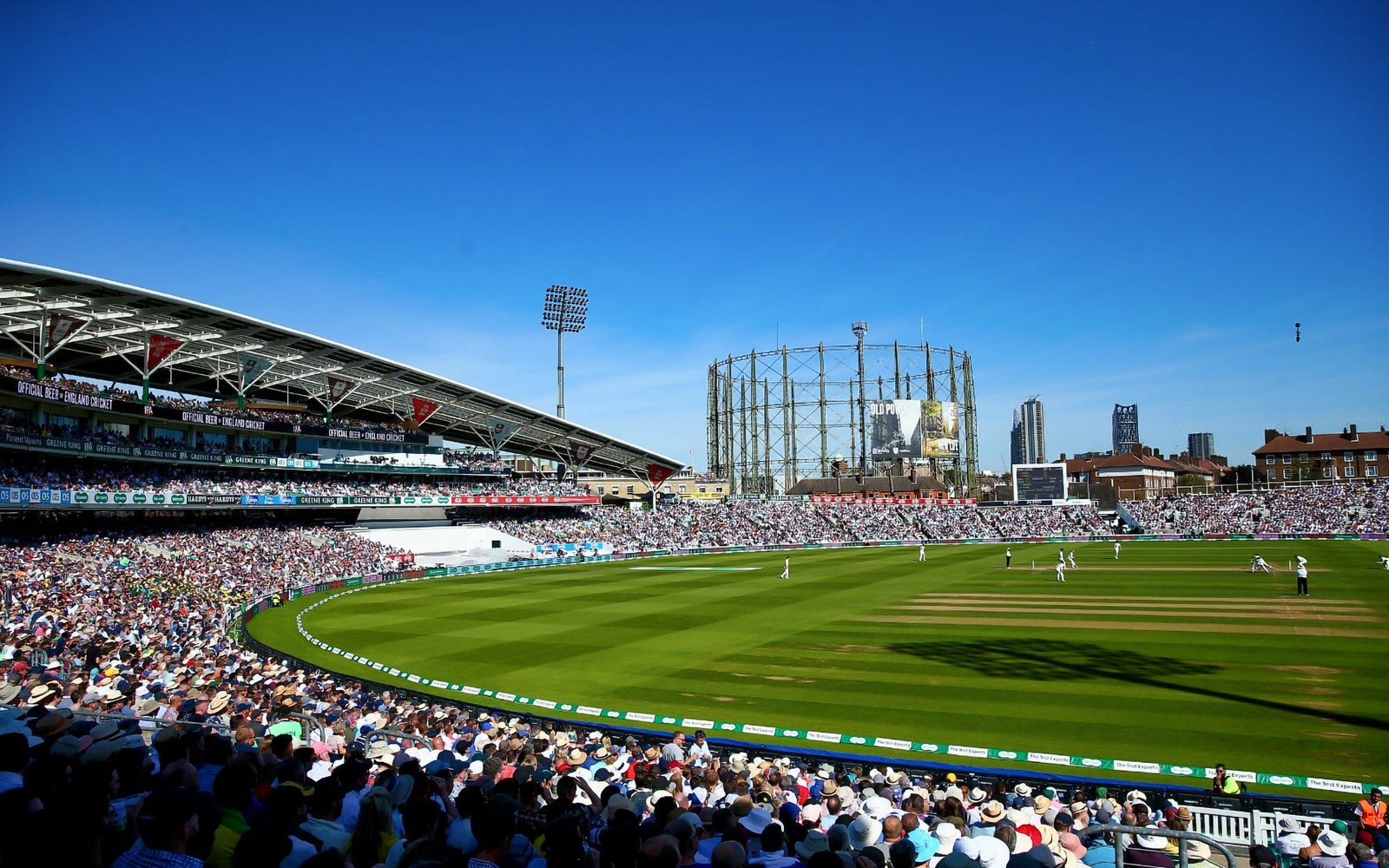 Cricket match at Kia Oval, London, with a packed crowd and iconic gas holder in the background.