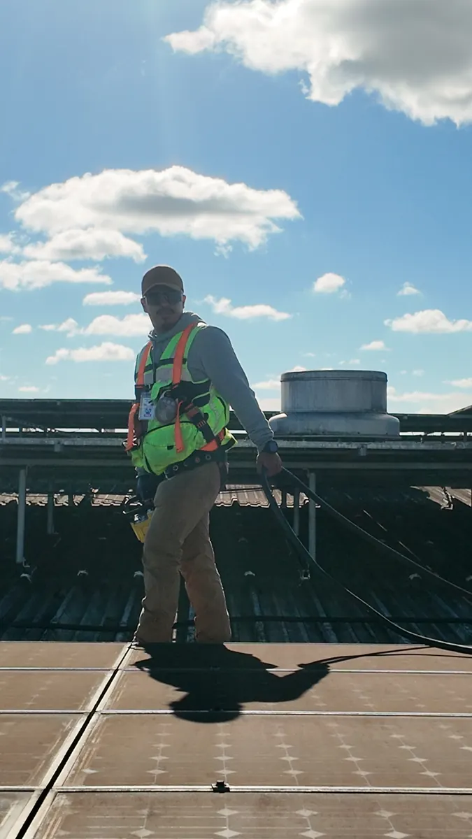 Crew member in a safety harness on a large commercial solar rooftop at Lange Twins