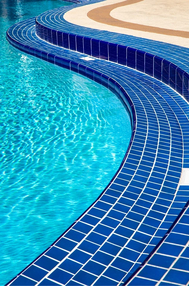 A close-up view of a curved swimming pool edge and blue tiles, representing premises liability investigations and compliance audits by Schwinghamer Law in Stockton.