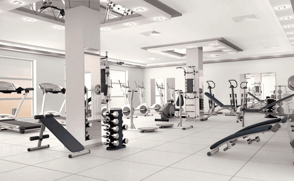 . A gym room featuring various exercise equipment and large mirrors reflecting the space.