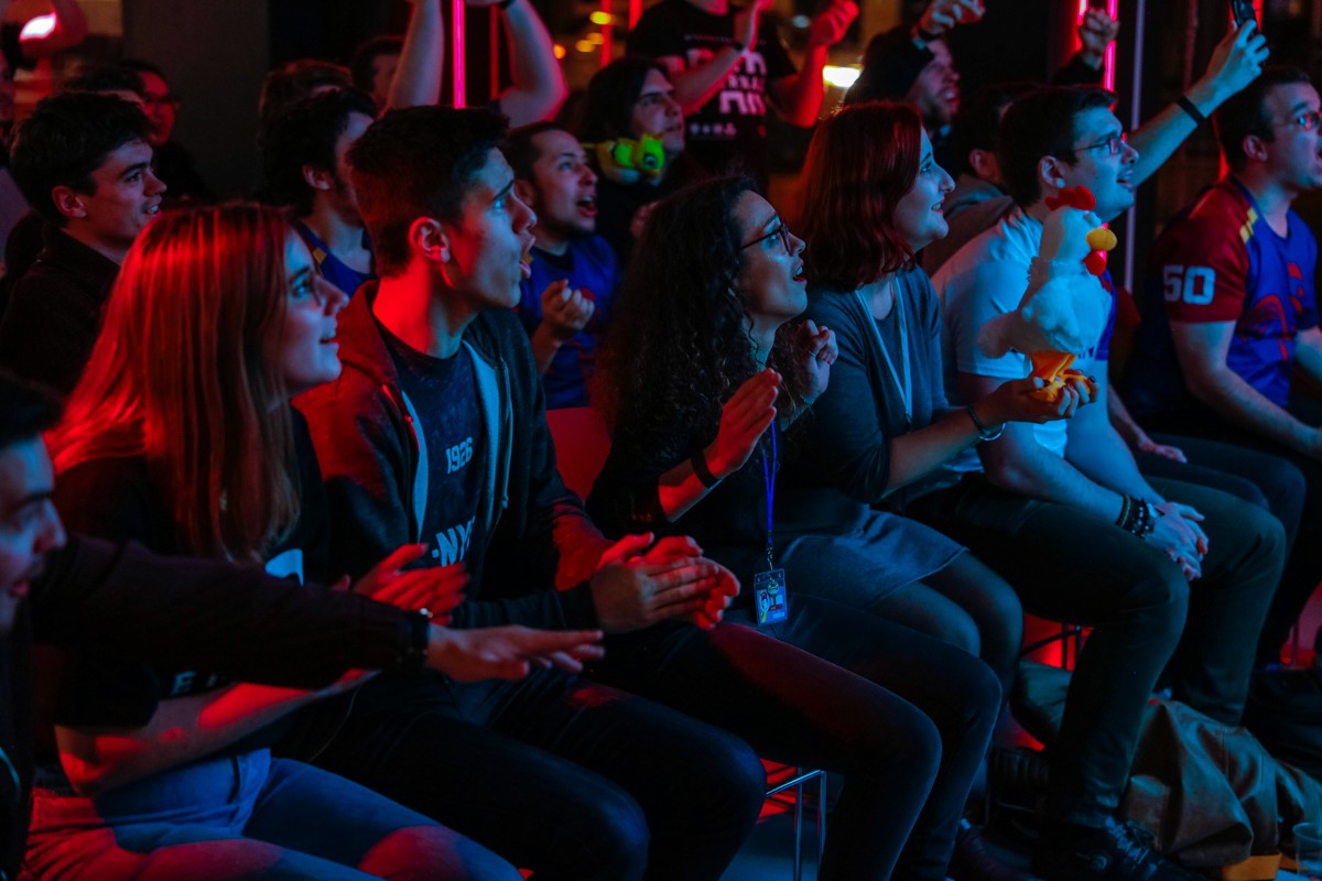 Crowd of supporters seated and watching a screen