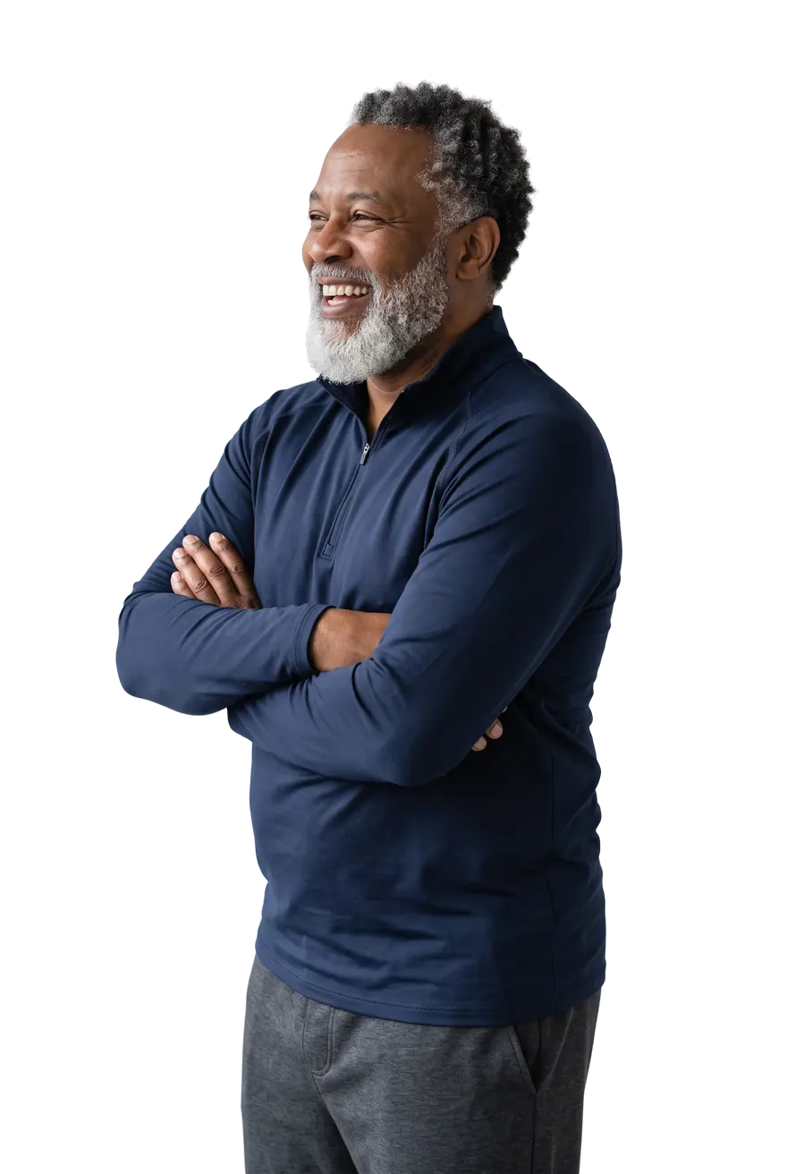 Smiling man with a gray beard standing with his arms crossed