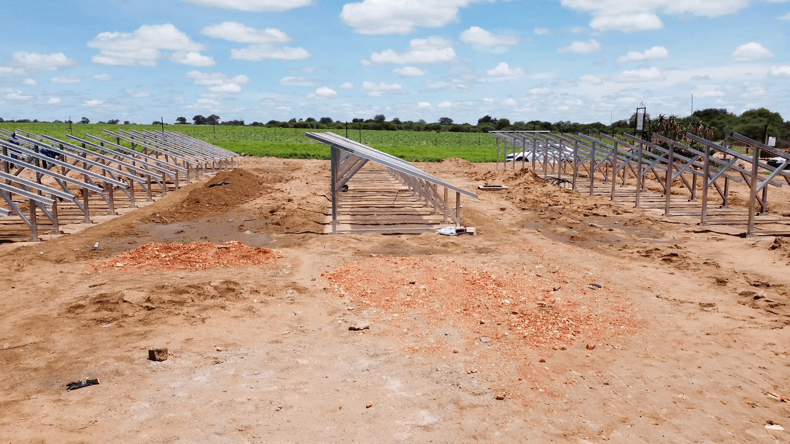 A woman is standing and speaking in a modern conference room with large windows. Two men are seated at a table with laptops, listening intently.