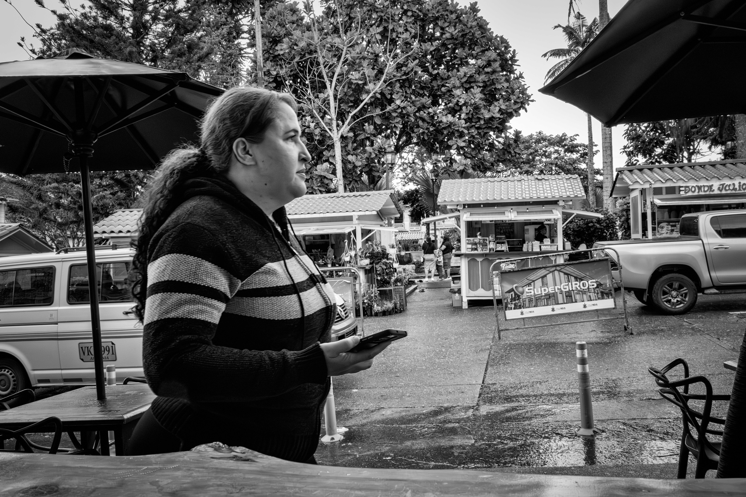 Rainy street scene with people passing by a bar window.