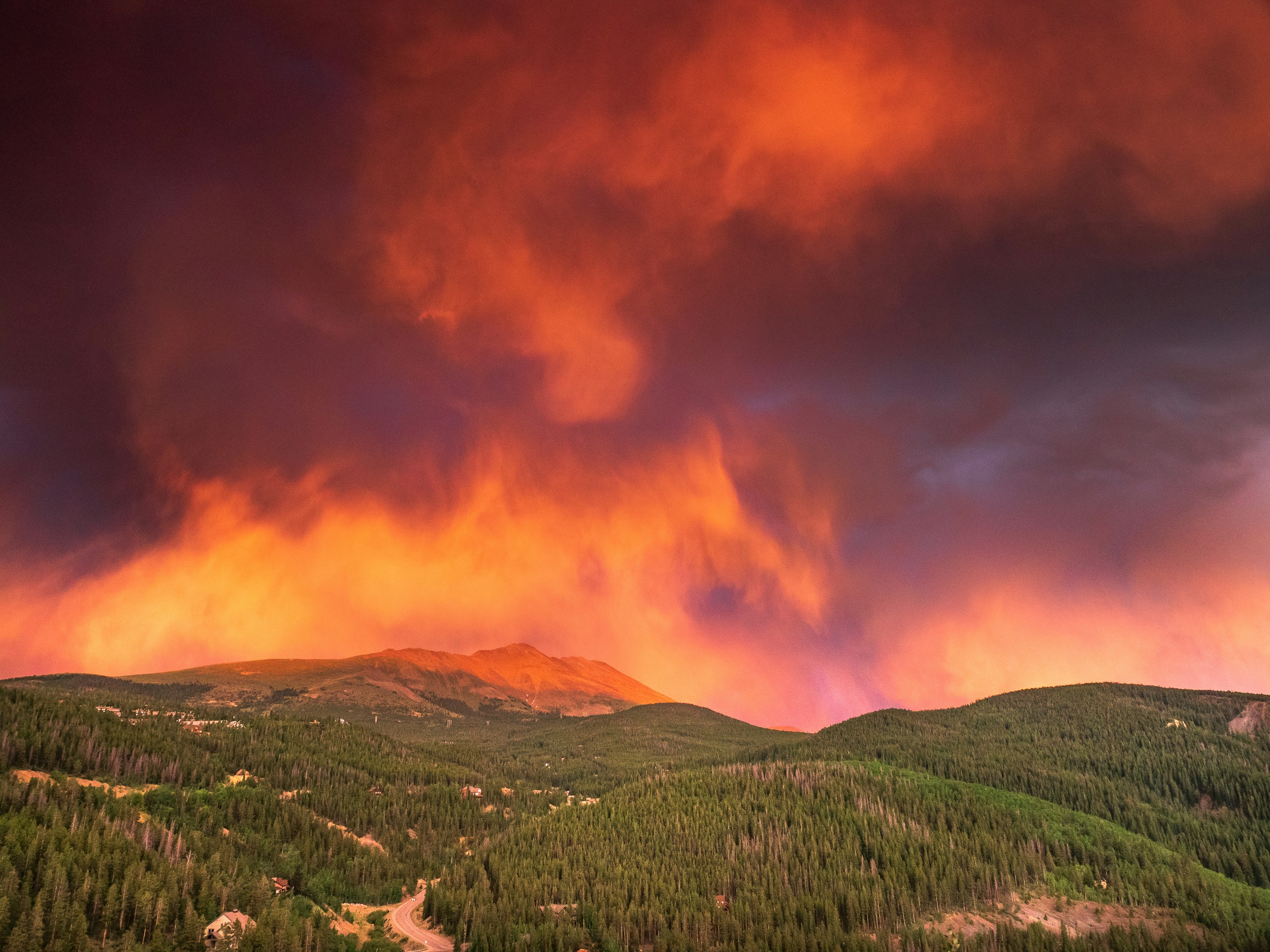 green trees and mountain under orange clouds