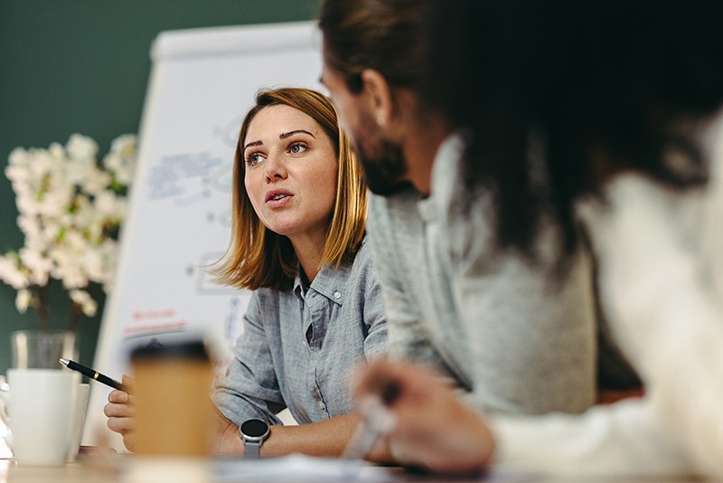 Meeting of colleagues having a discussion with a whiteboard easel in the background