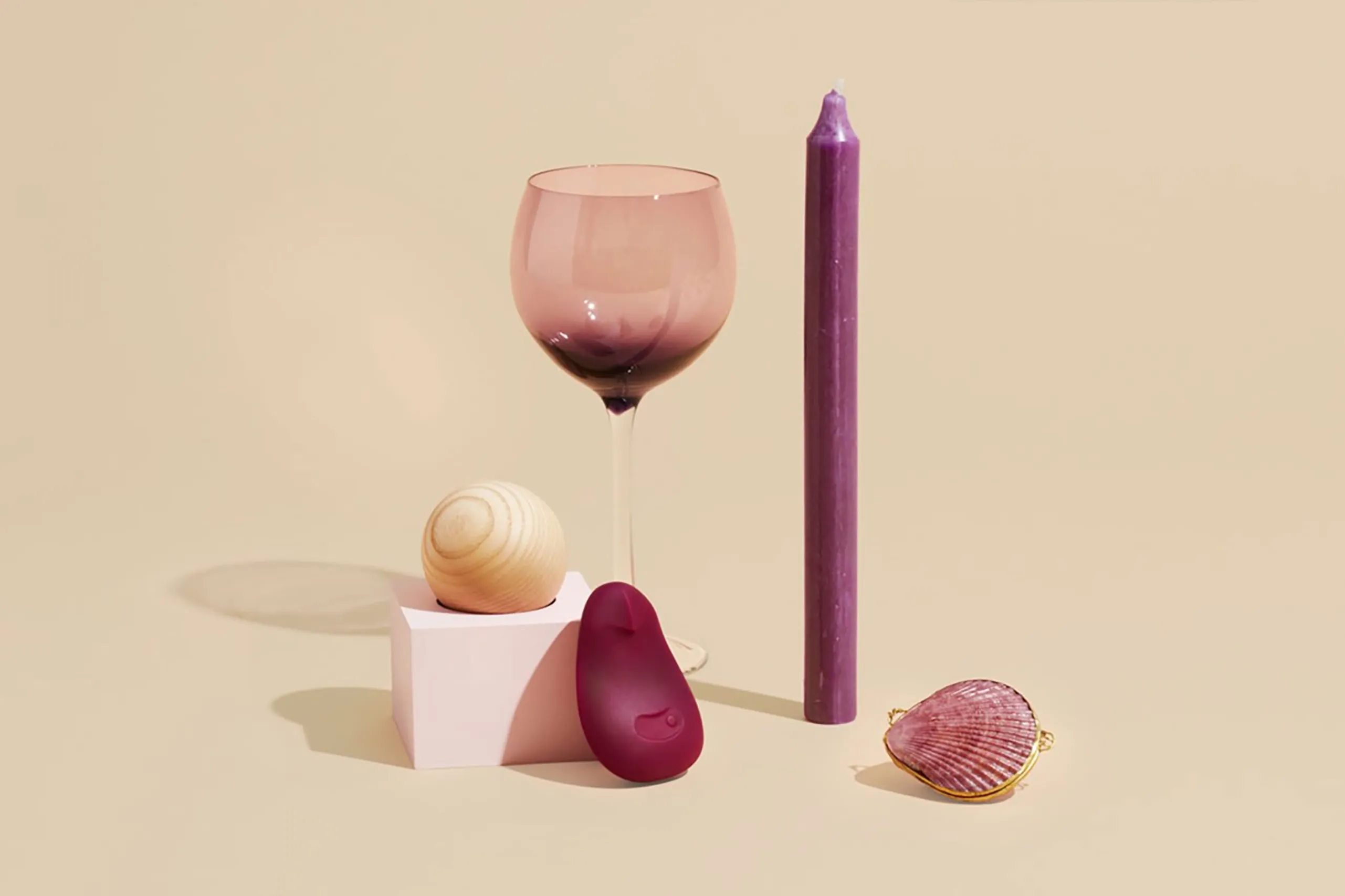 Burgundy Dame Pom displayed with a candle, glassware, and decorative objects on beige