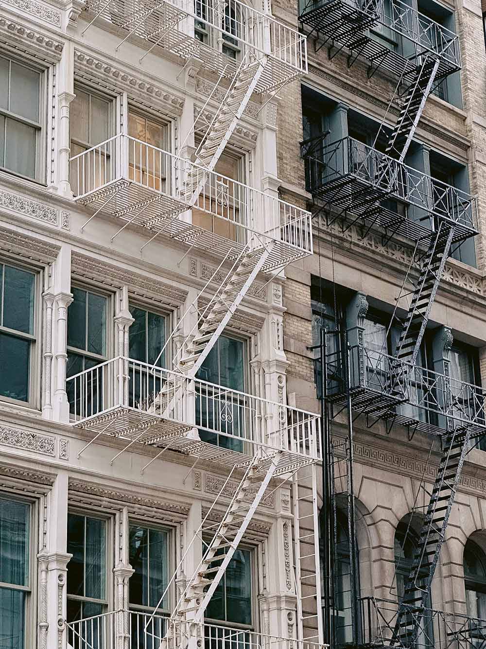 Tall stone New York apartment buildings with fire escape landings and ladders