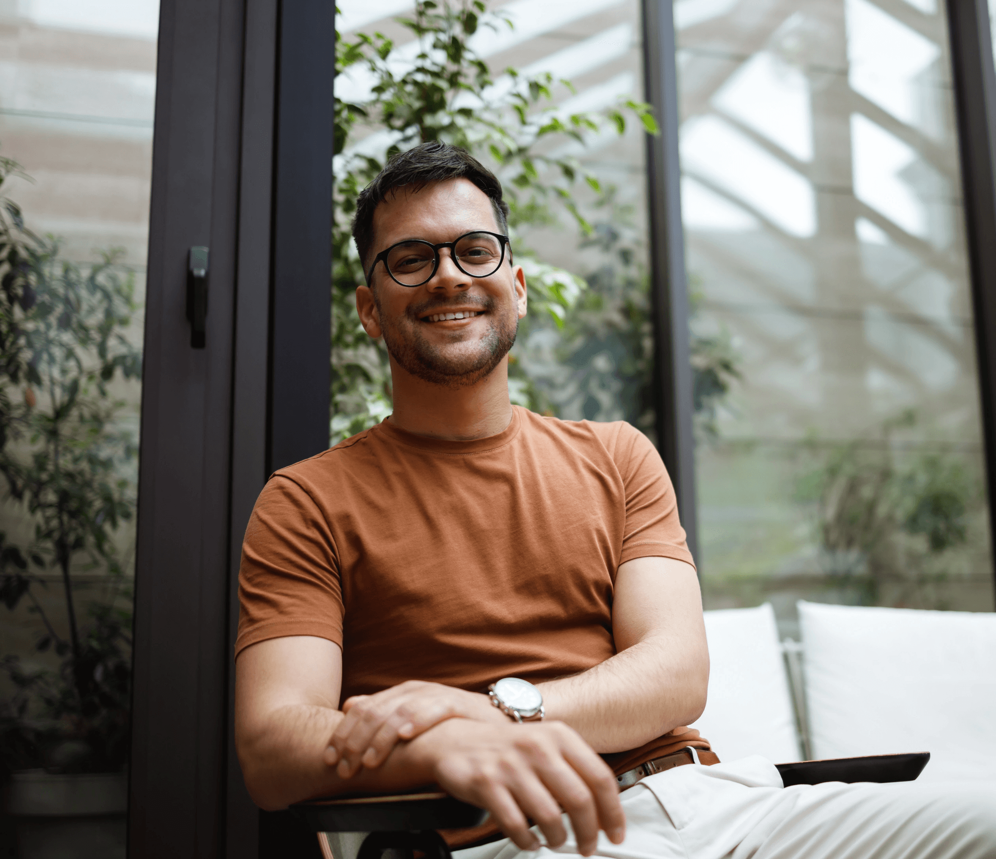 Young man sitting on a chair smiling with his arms crossed