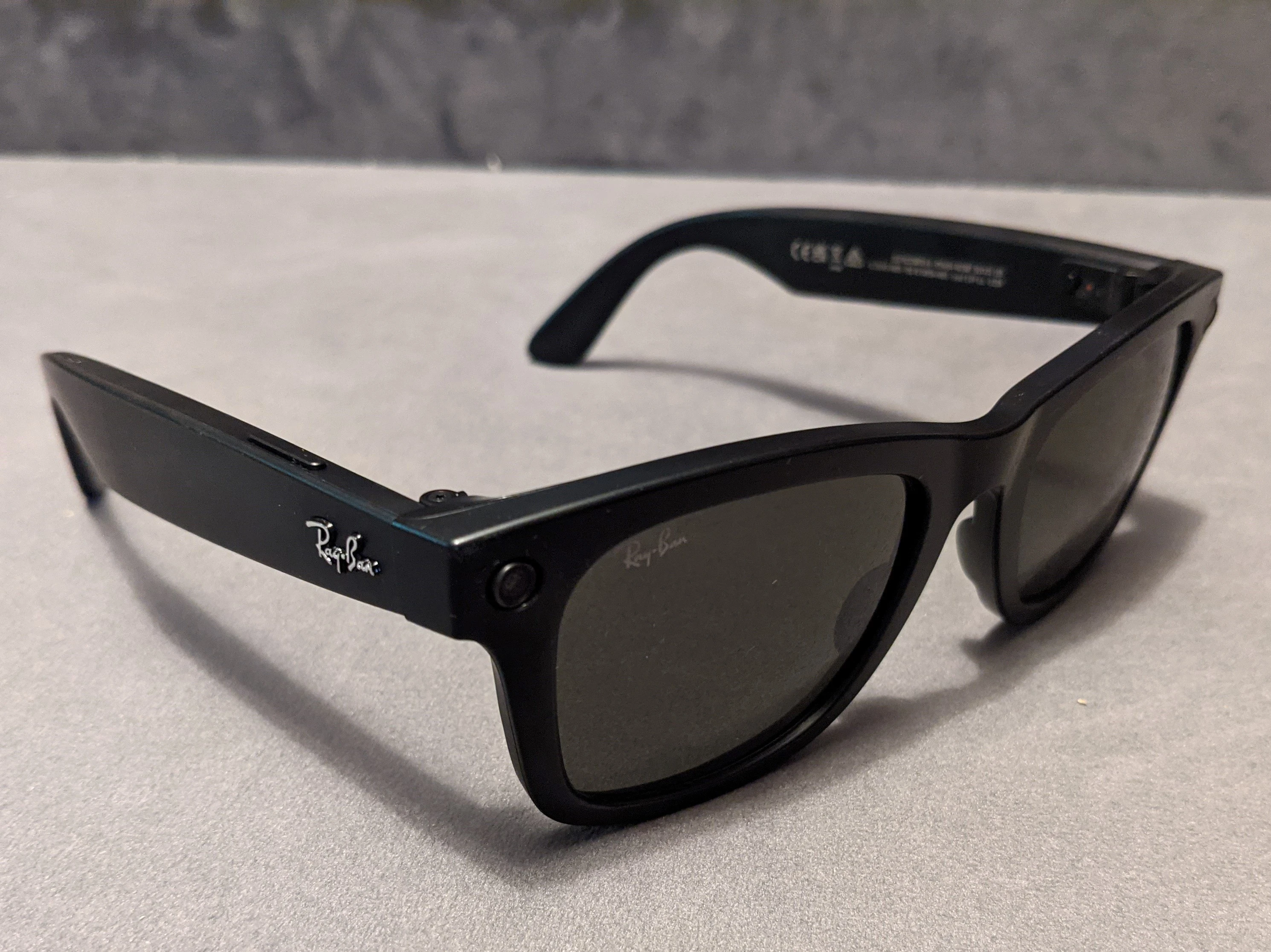 Black first-generation Ray-Ban Stories smart sunglasses resting on a tabletop, with the camera built into the frame.