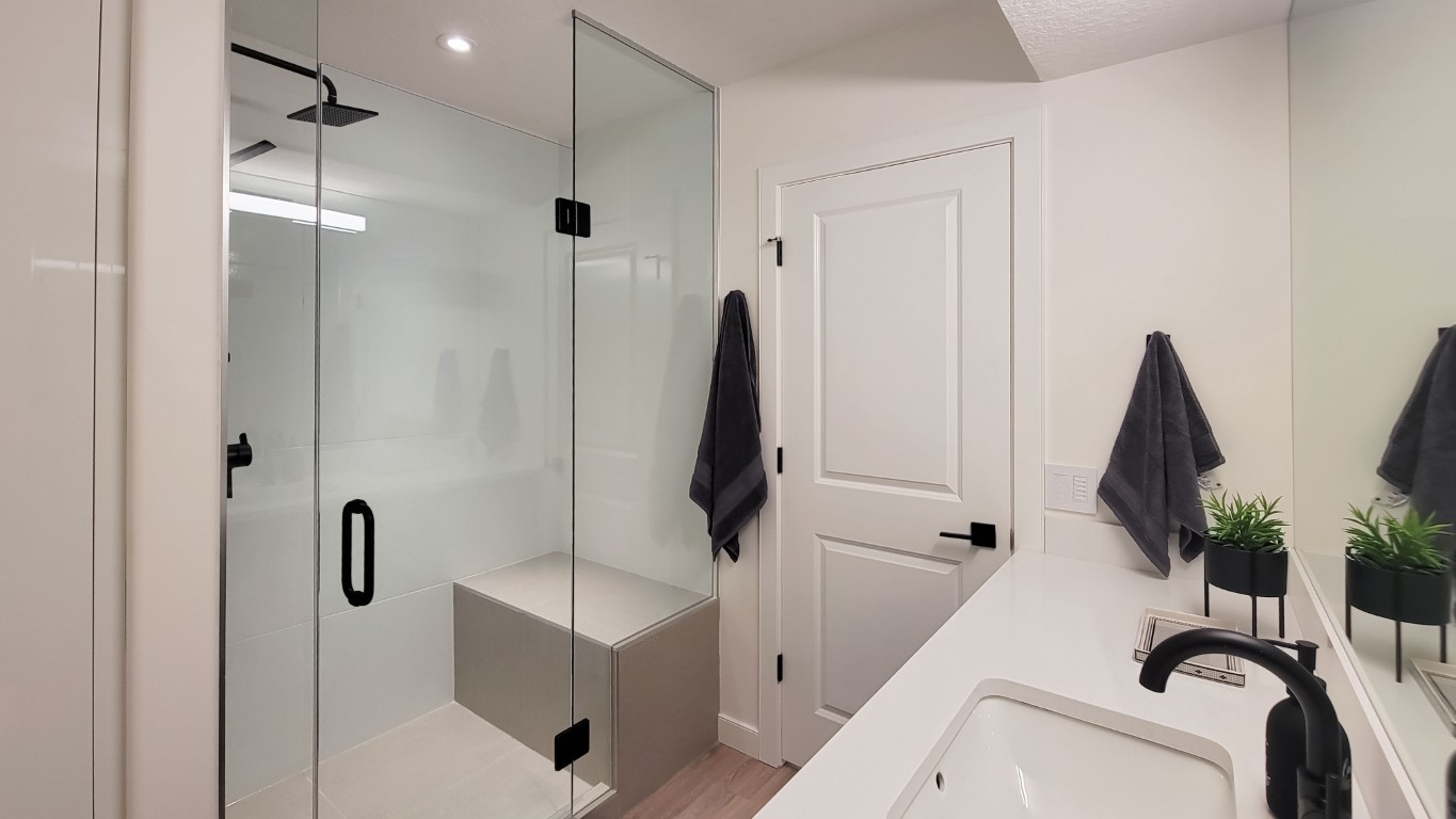 Image of KHD Homes primary ensuite bathroom with modern glass shower, black fixtures, and spa-like ambiance.