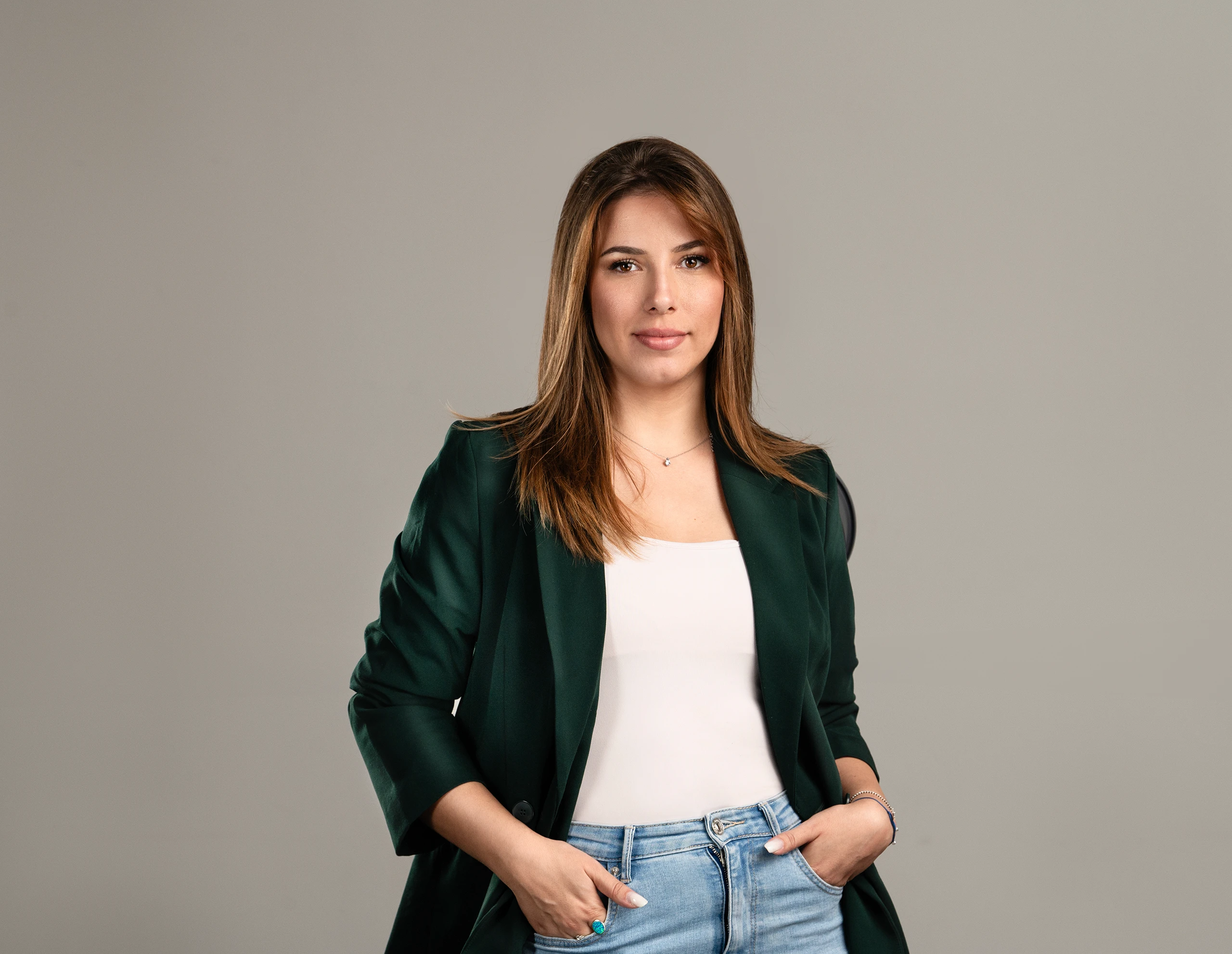 Opušteni portret žene koja nosi tamnozeleni sako preko bele majice