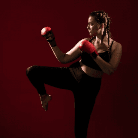 A woman in a boxing pose wearing red boxing gloves