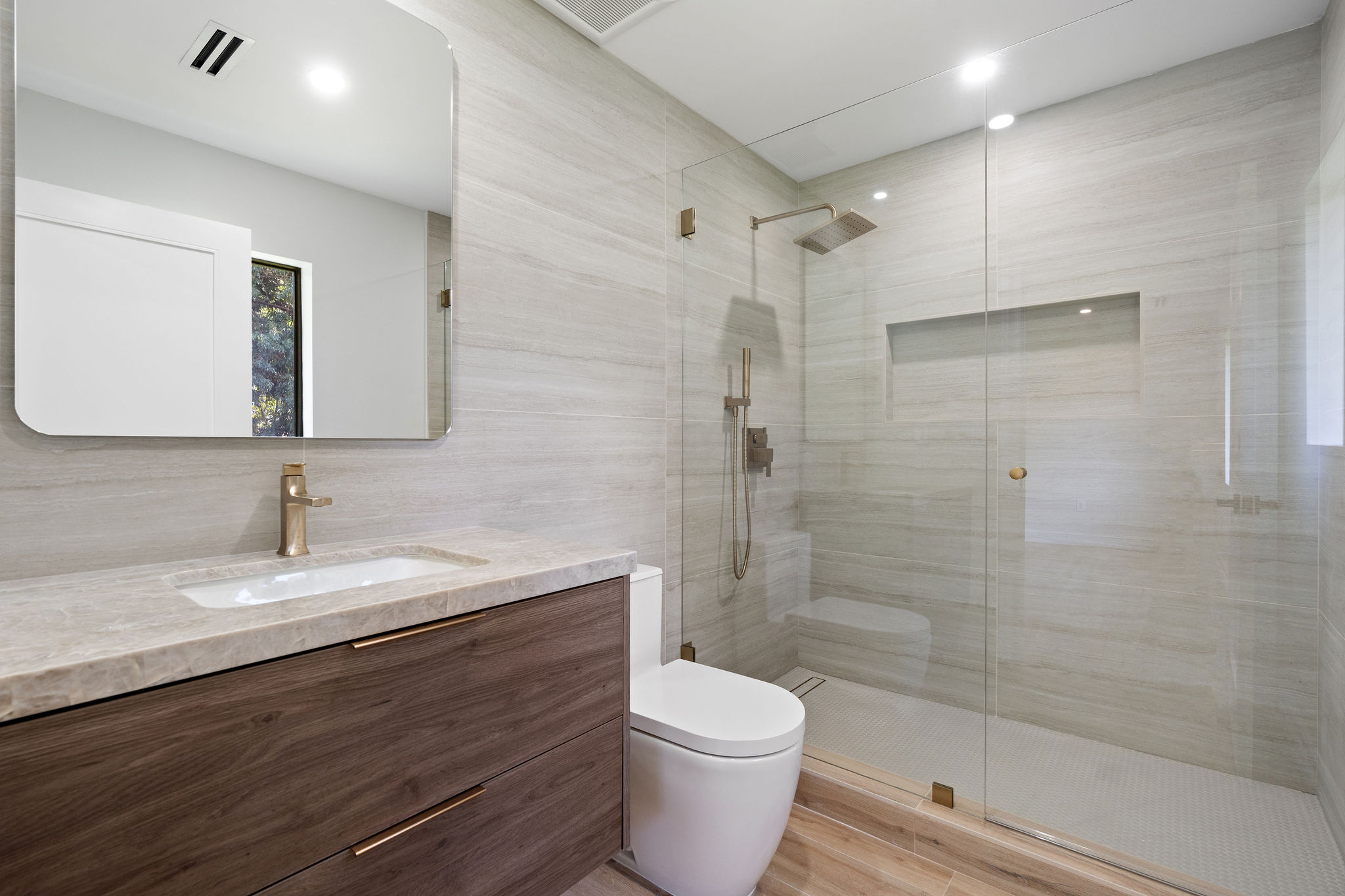 Modern bathroom with a floating vanity, glass-enclosed shower, and marble tile.