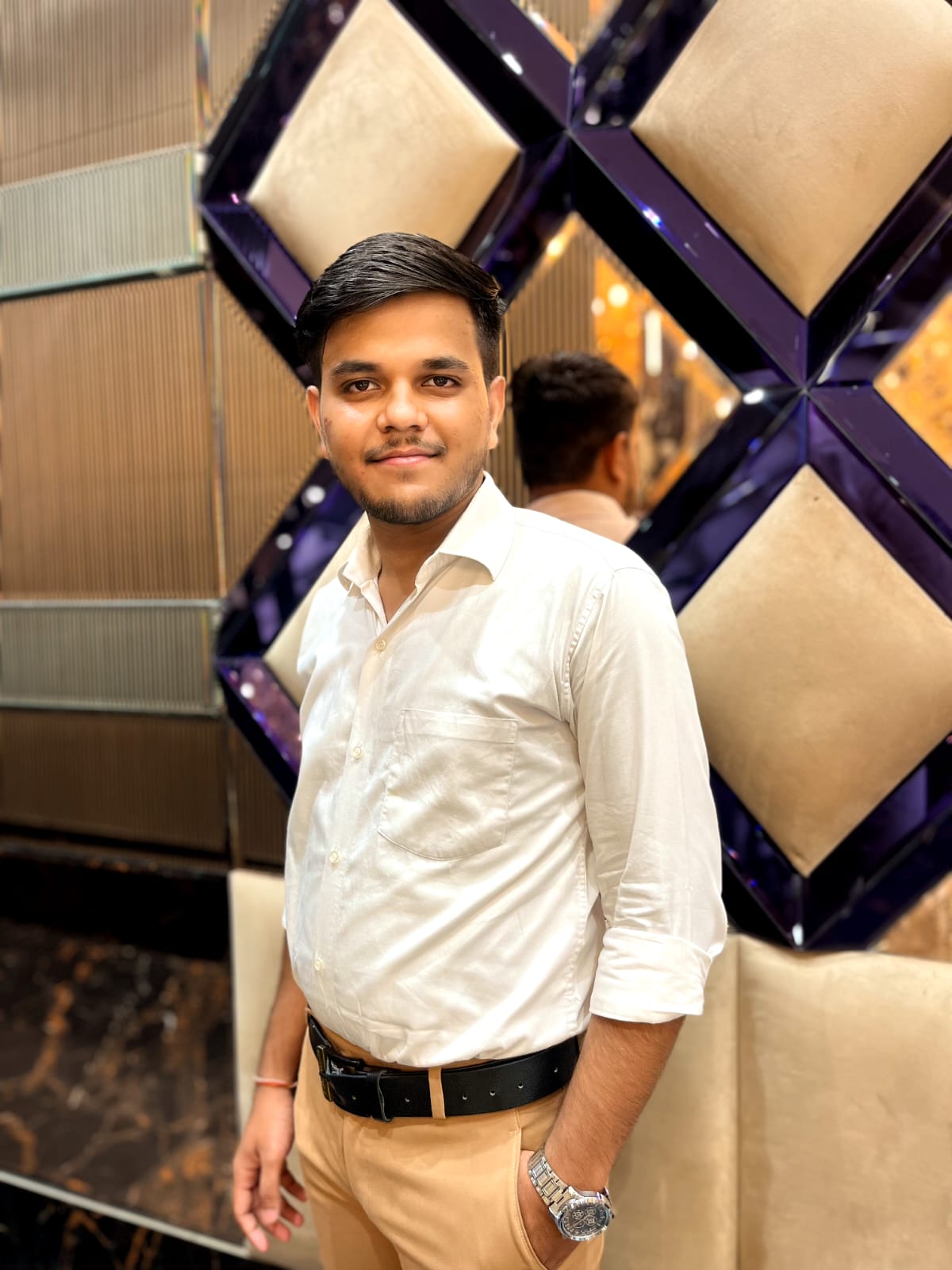 a man wearing glasses and a blazer with a lighting that casts a soft shadow on the wall behind him