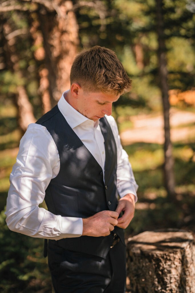 Groom getting ready outdoors adjusting vest at Smith Cabin Aspen wedding