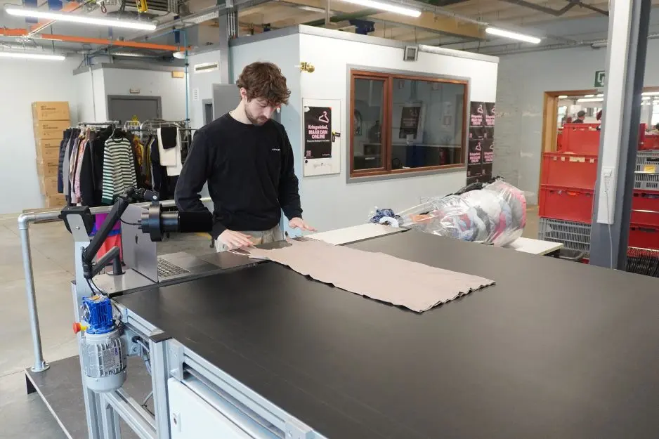 High-throughput textile sorting with Sort Mate: An operator feeding a garment into the automated AI grading system for efficient processing.