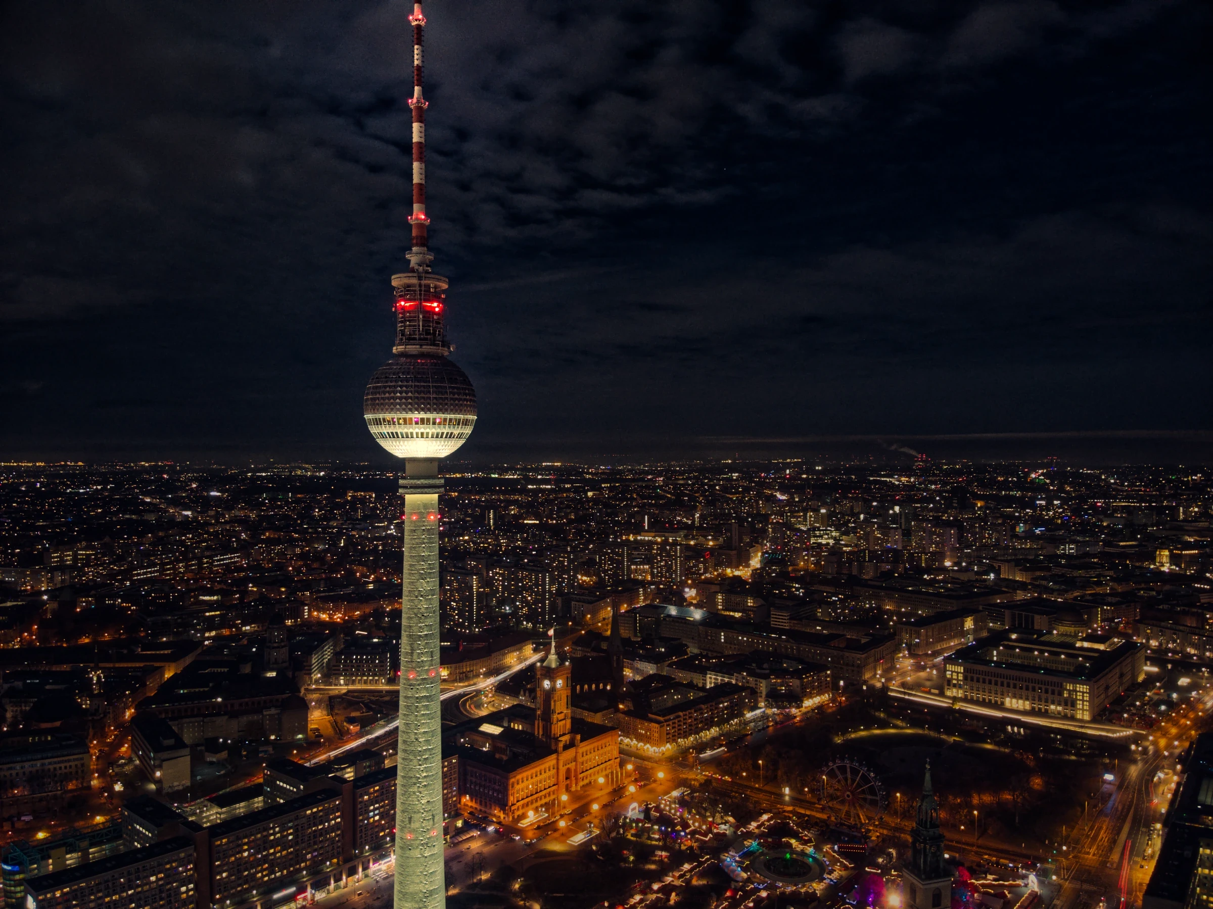 Architekturfotografie des Berliner Fernsehturms bei Nacht mit Blick über das Stadtzentrum, das Rote Rathaus und die beleuchteten Straßen Berlins.