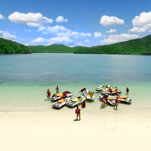 穿著泳衣的人們聚集在沙灘上的係靠水上摩托的碼頭，周圍是一個平靜清澈的湖泊，四周環繞著綠色的山丘。