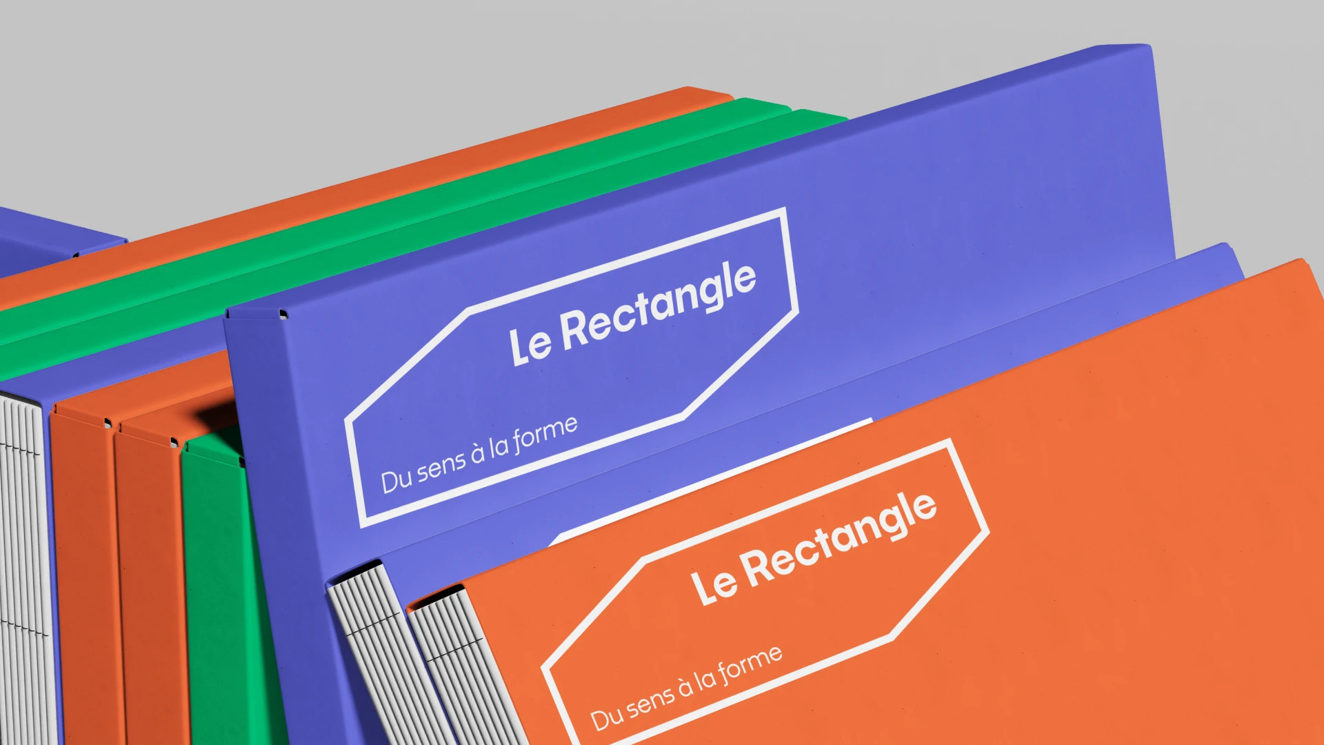 Mockup classeurs Le Rectangle déclinés dans les trois couleurs de la palette — bleu, vert, orange avec logo blanc, application du système graphique modulaire, Tartelette Concept graphiste Toulouse