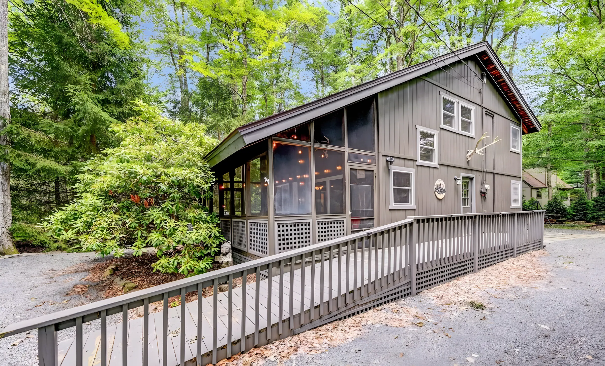 Gray chalet with screened porch and ramp walkway in the woods at Mountain MAMA, Lake Naomi, Pocono Pines
