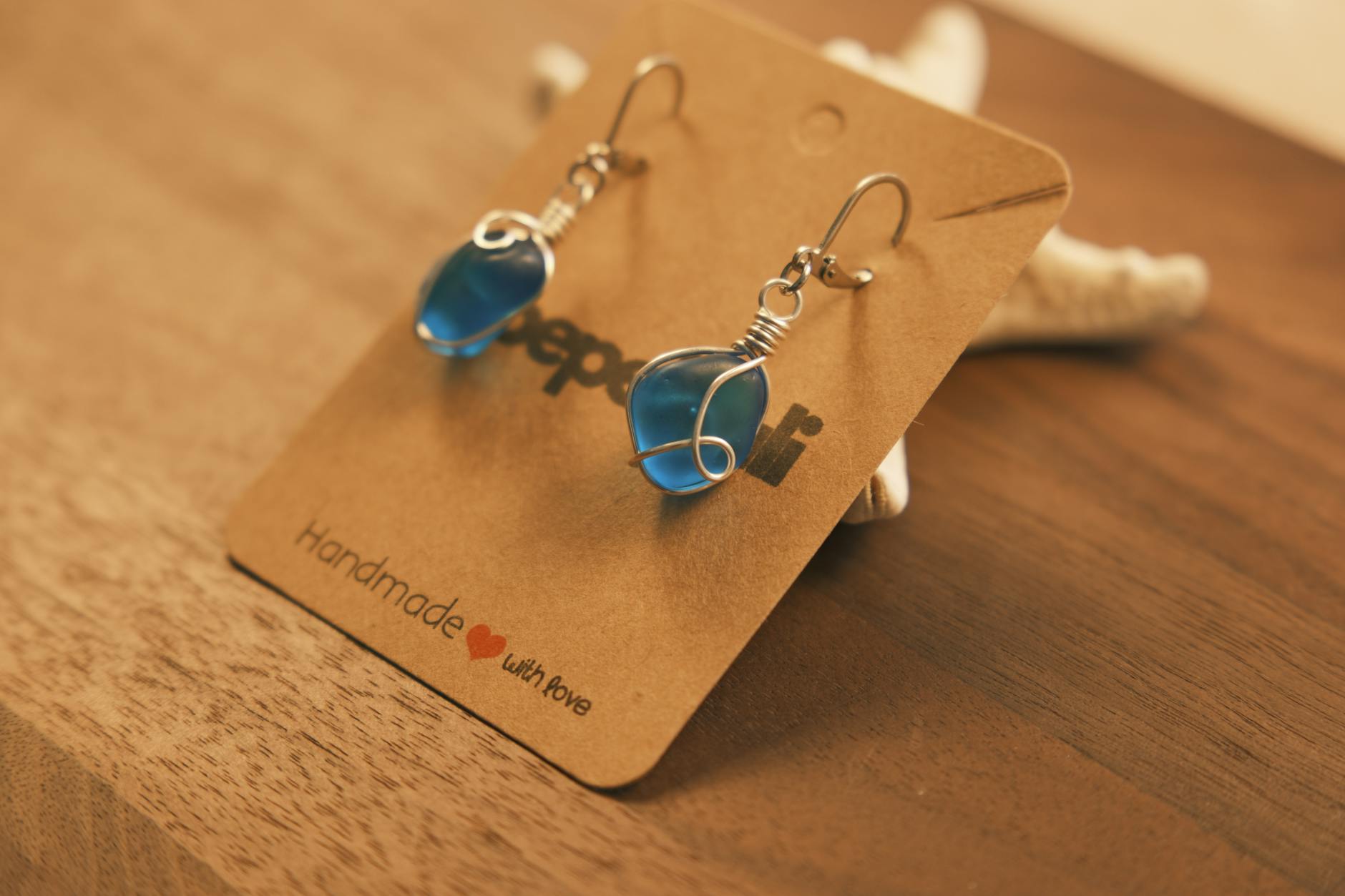 Chic handmade earrings featuring blue stones wrapped in wire on a brown background.
